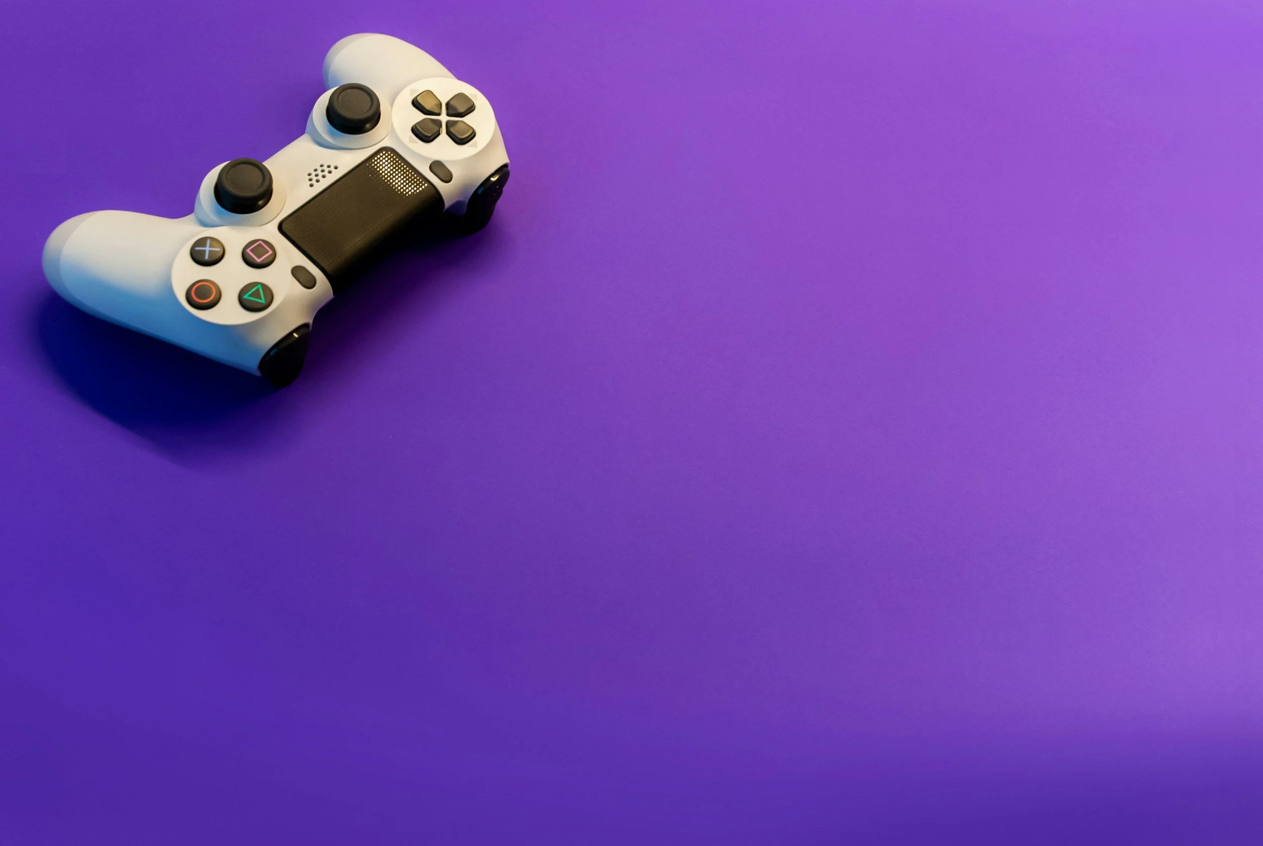 A white and black video game controller on a purple background.