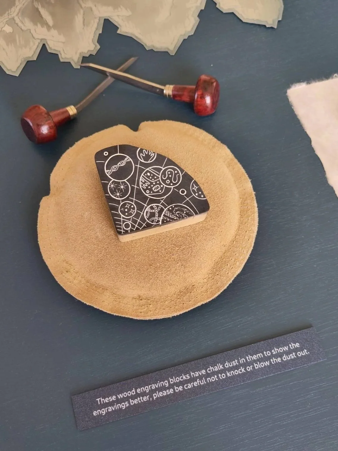 wood engraving block shown with engraving tools, space themed images carved in