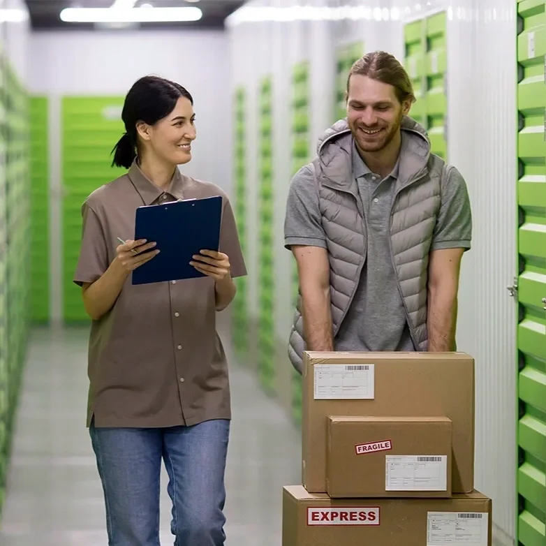 Self-storage employee helping a tenant move boxes through a storage facility.
