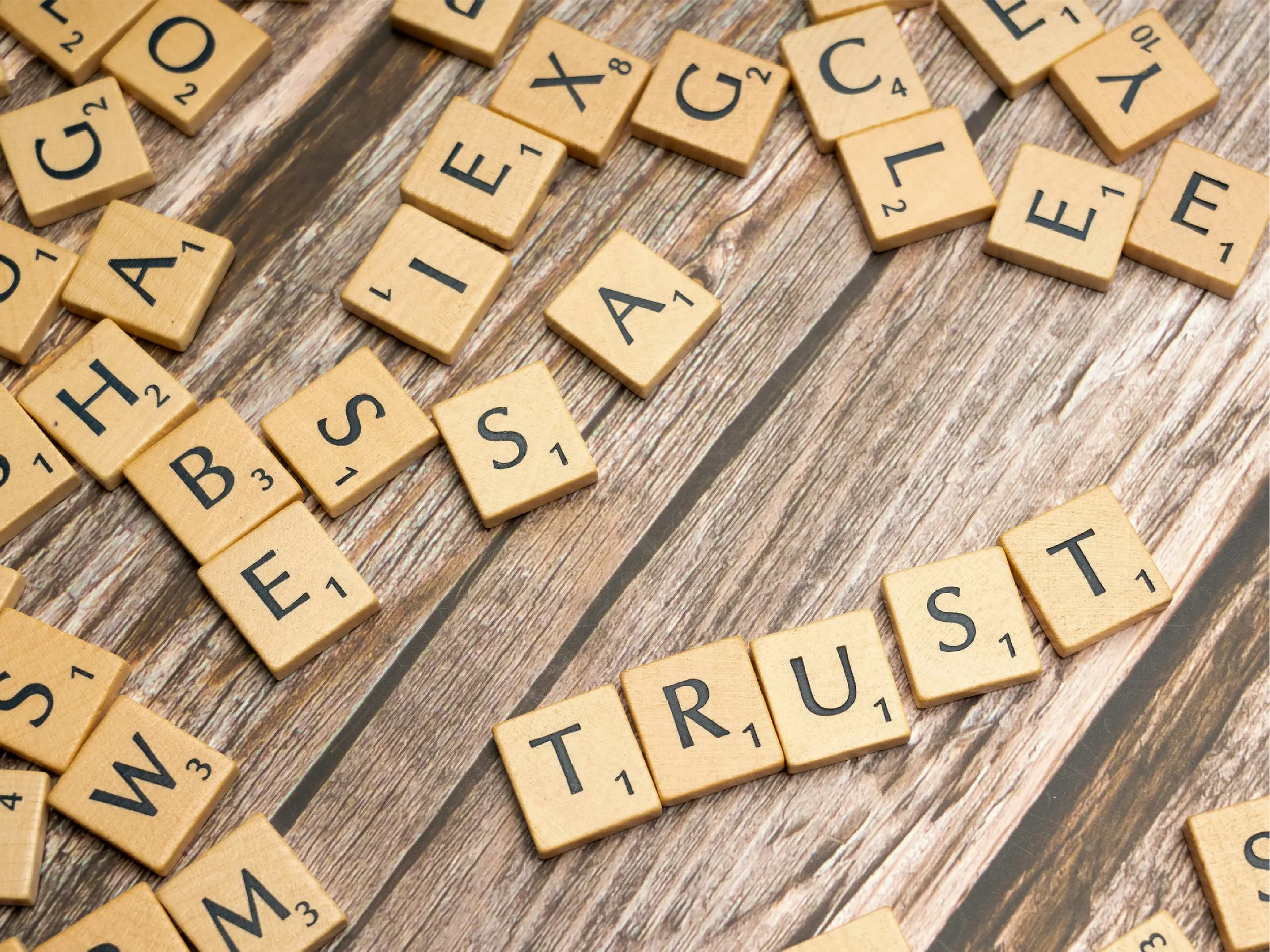 Scrabble-style letter tiles spelling the word “TRUST” on a wooden surface, symbolizing trust, ethics, and strong relationships in international business and offshoring.