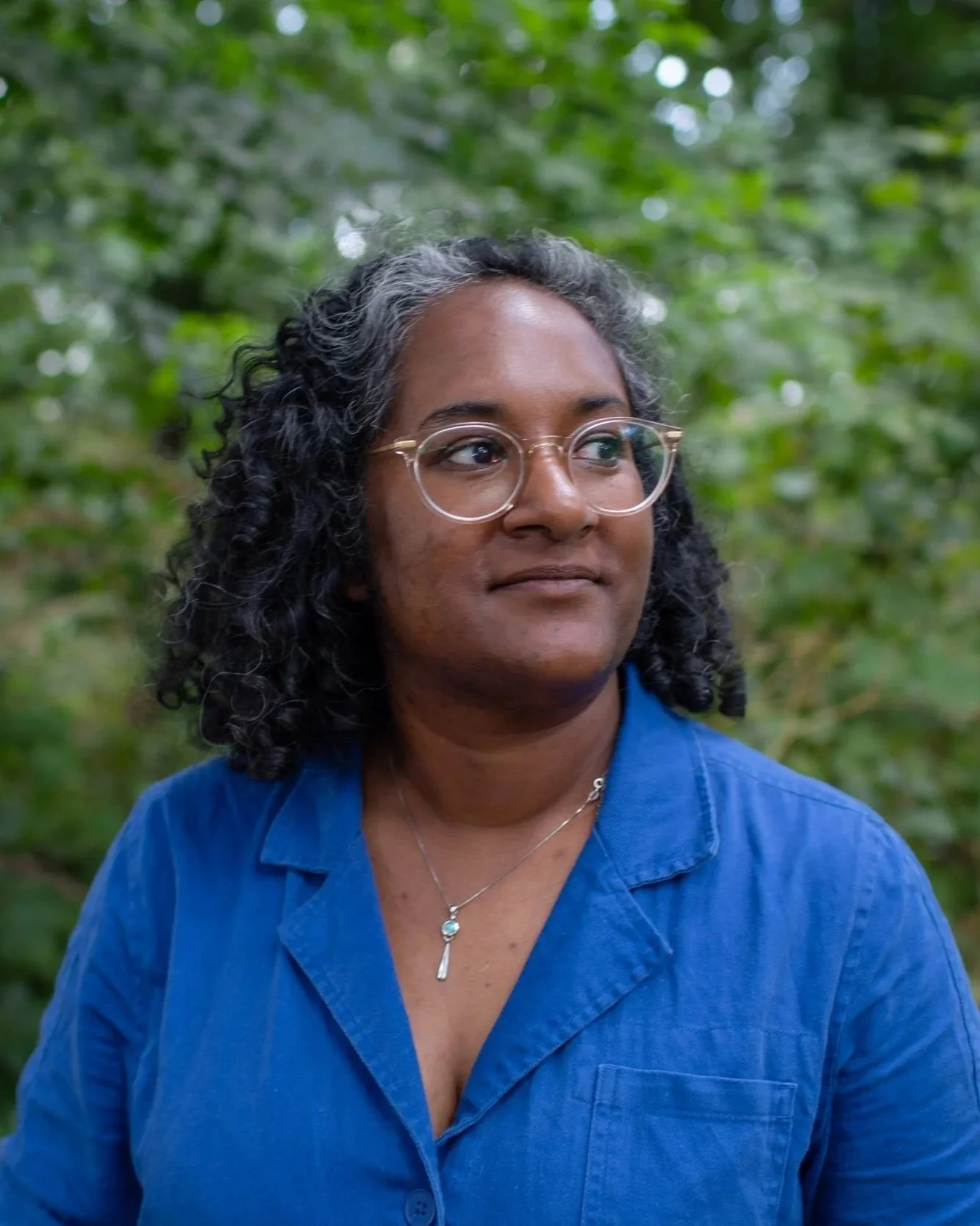 headshot of a woman in front of a tree looking off to the right