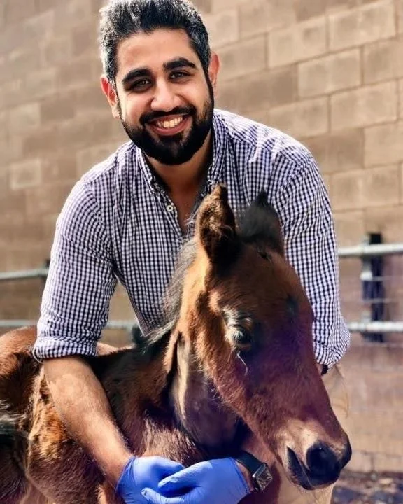 man smiling into the camera holding a small horse