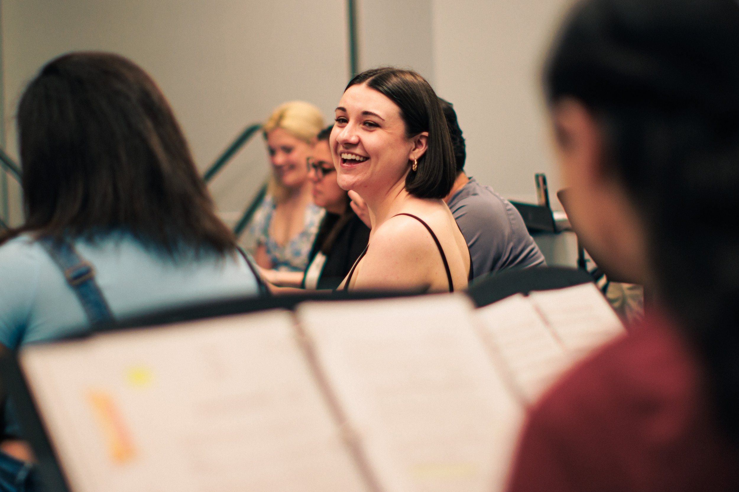 Group of women sitting around a table, smiling and engaging in conversation at a professional event or conference.