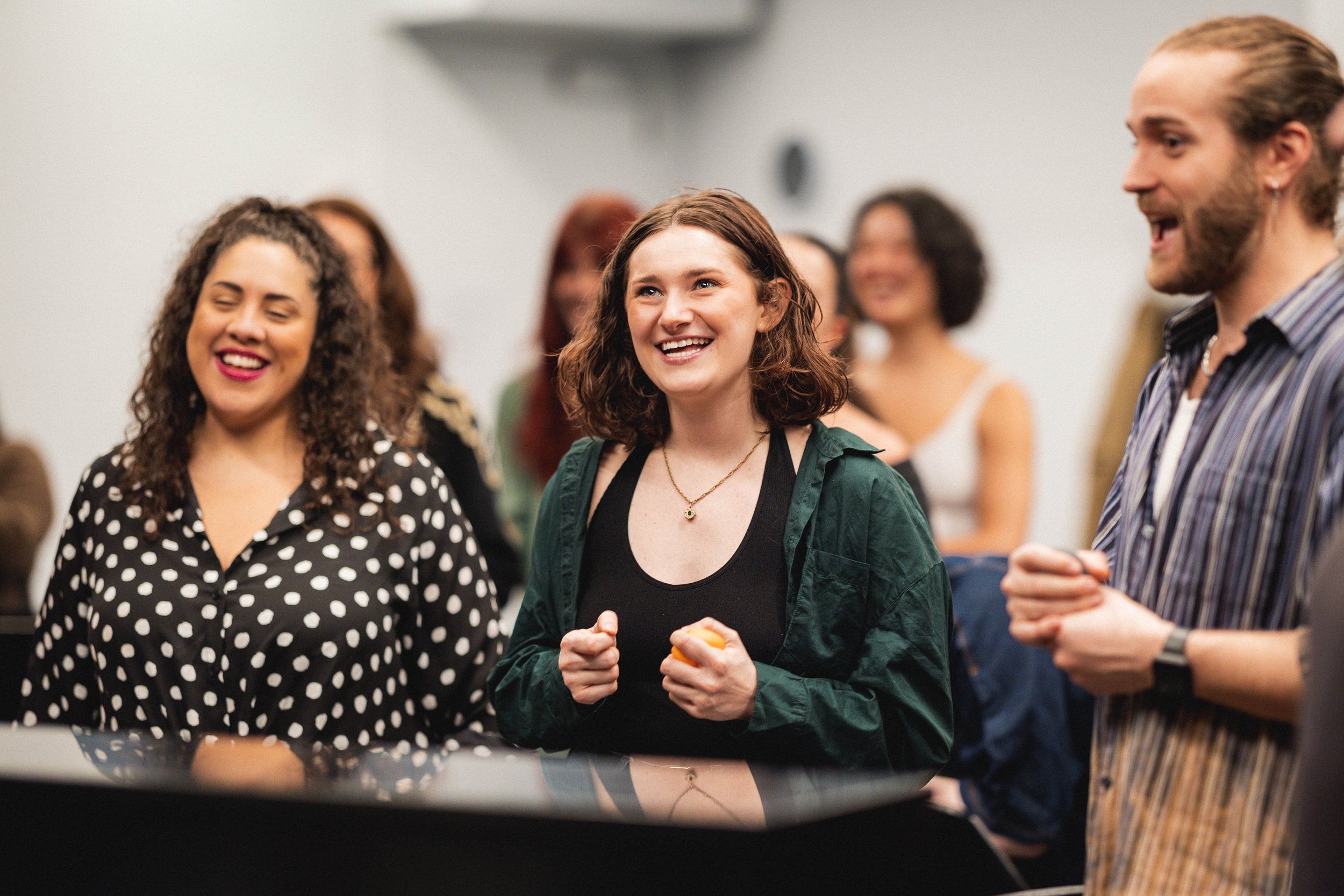 Group of smiling people talking and laughing indoors at a social gathering.