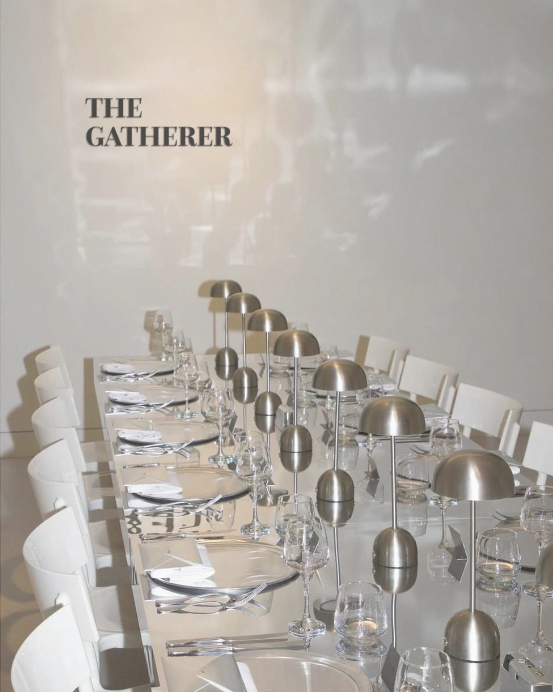Elegant dining table set with white chairs, plates, glasses, and modern silver dome lamps.