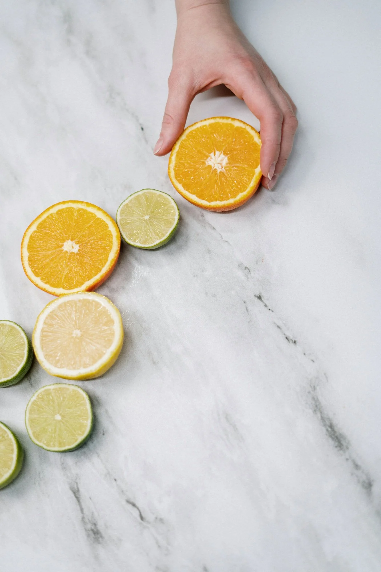 Hand holding an orange with sliced citrus fruits, visual for menstrual cycle regulation and hormonal balance.