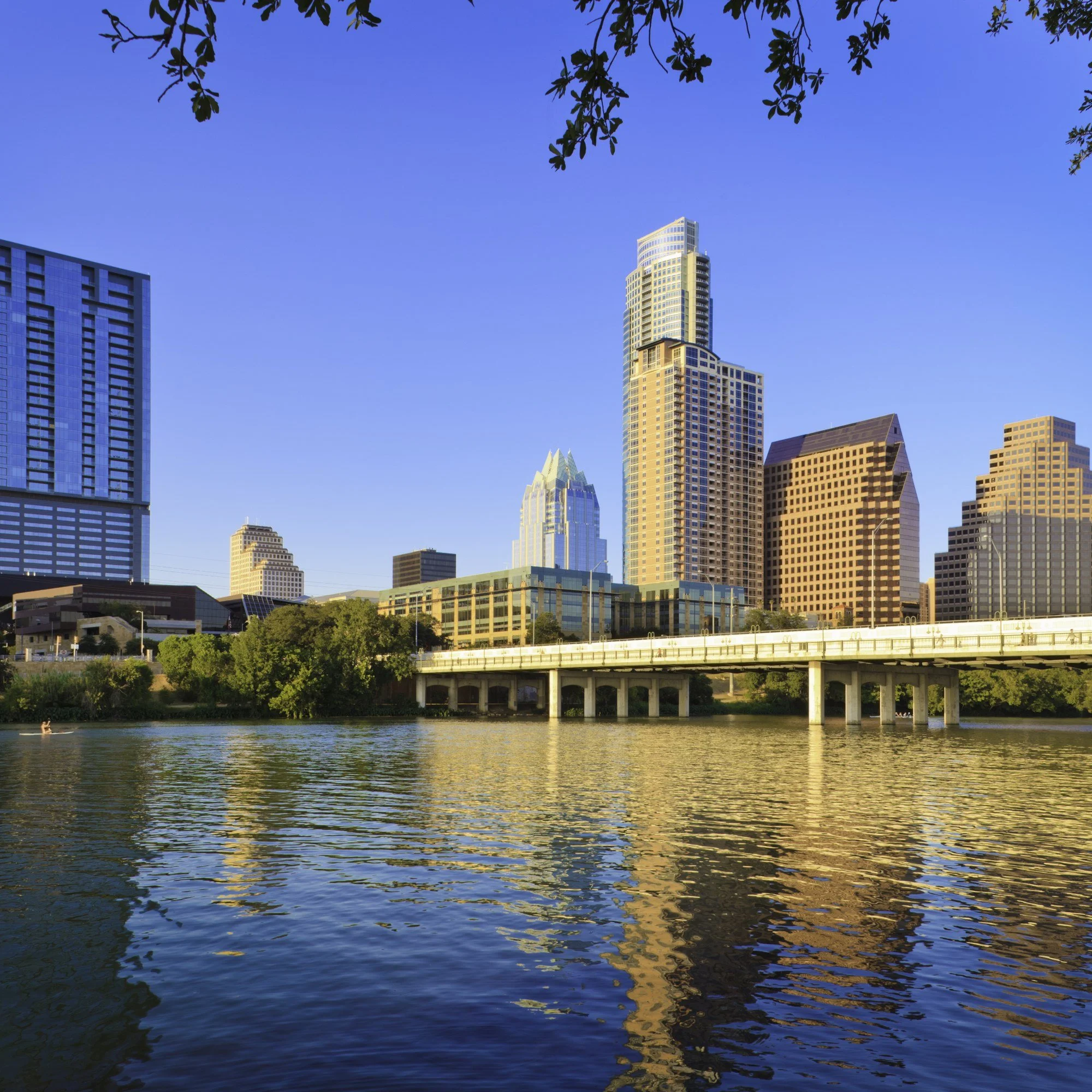 The Austin, Texas, skyline and the First Street Bridge reflected in the water.