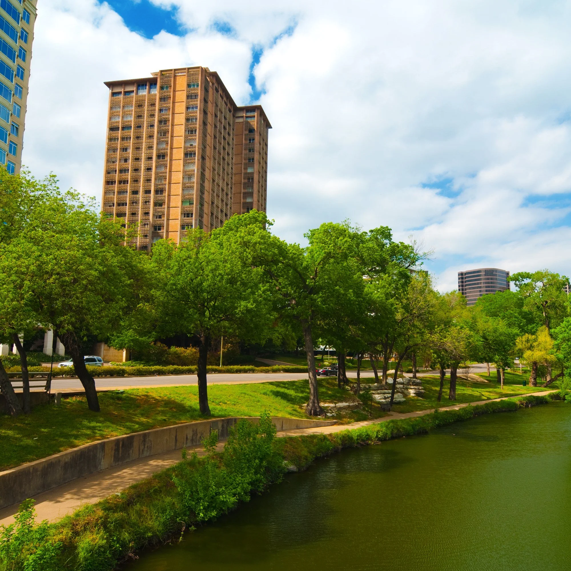 Turtle Creek in the Oak Lawn neighborhood of Dallas, Texas, with a high-rise above the trees.