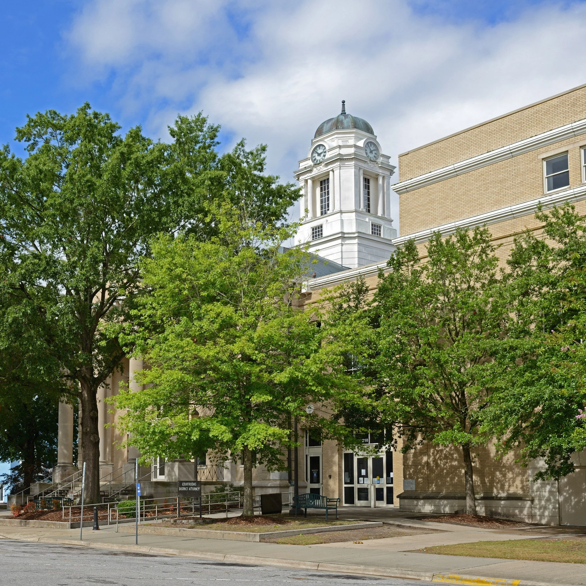 The historic Pitt County Courthouse in Greenville, North Carolina, with its clock tower above a row of trees.