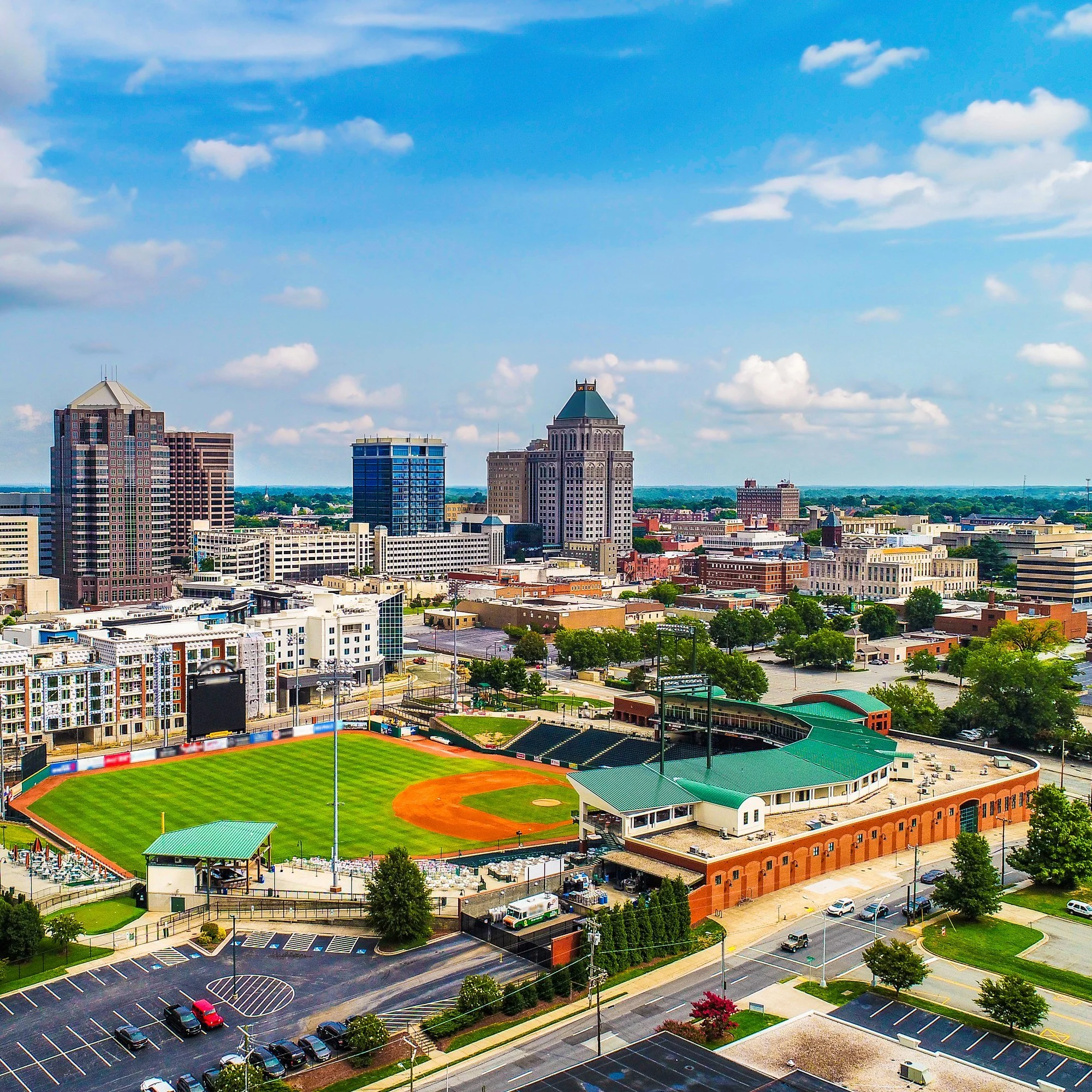 Aerial view of downtown Greensboro, North Carolina, with a baseball stadium in the foreground.