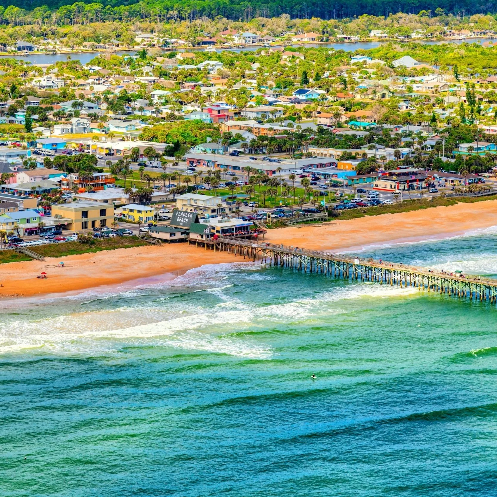 Aerial view of Flagler Beach, Florida, with the pier reaching into the Atlantic Ocean and the oceanfront town behind it.