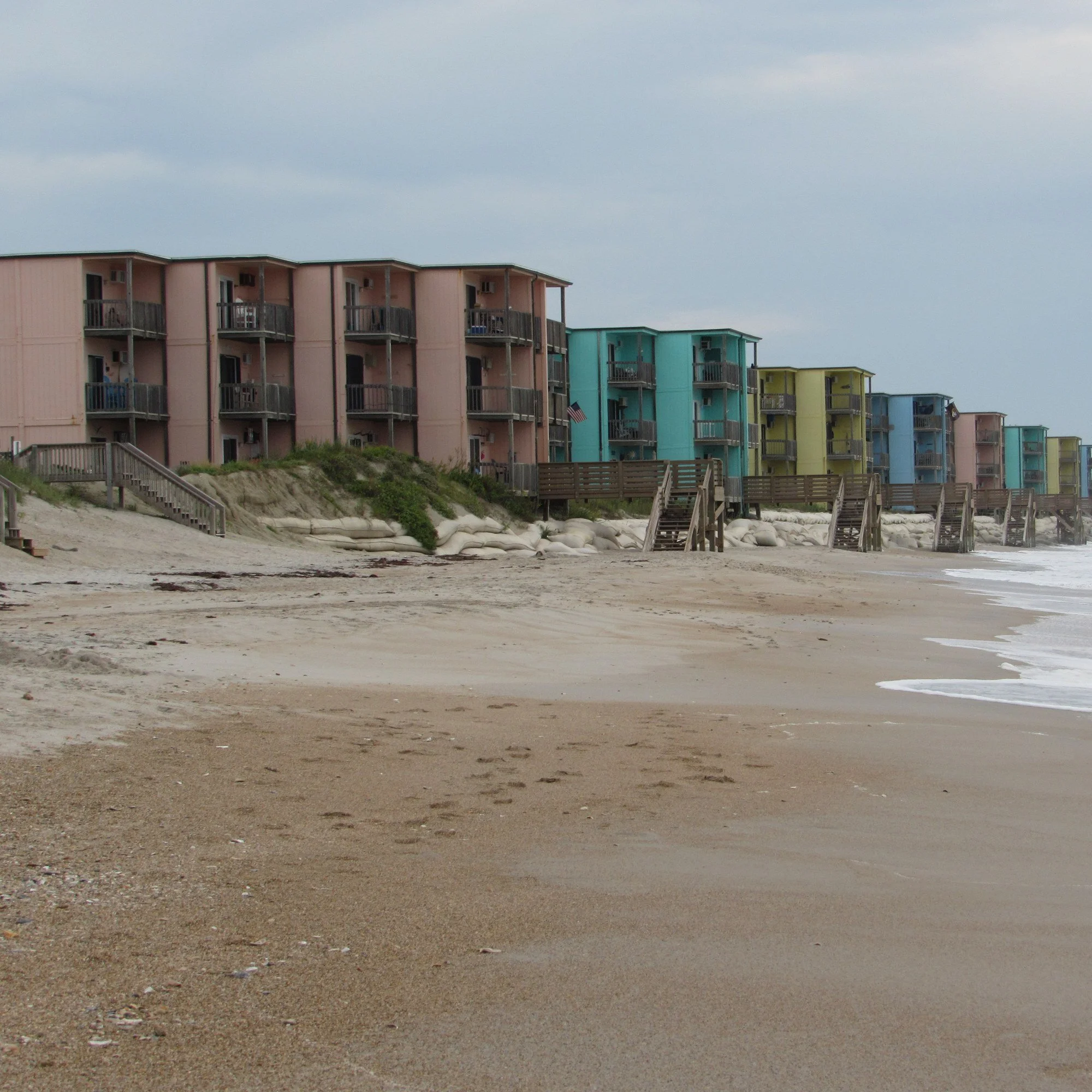 A row of pink, green, yellow, and blue houses along the beach at North Topsail Beach, North Carolina.