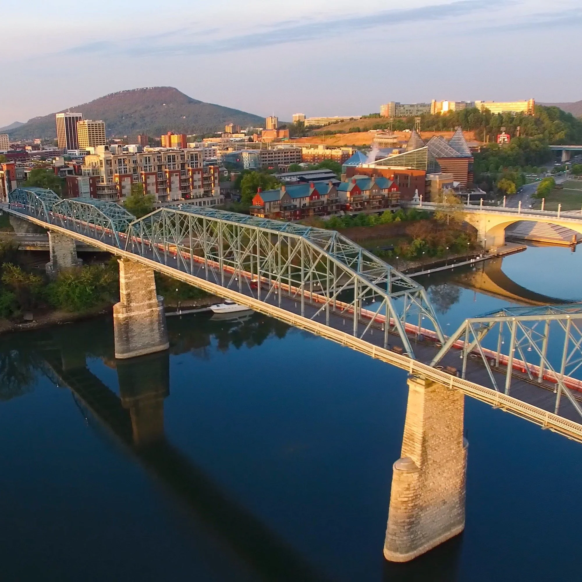 Bridges crossing the river in downtown Chattanooga, Tennessee, with a mountain in the distance.