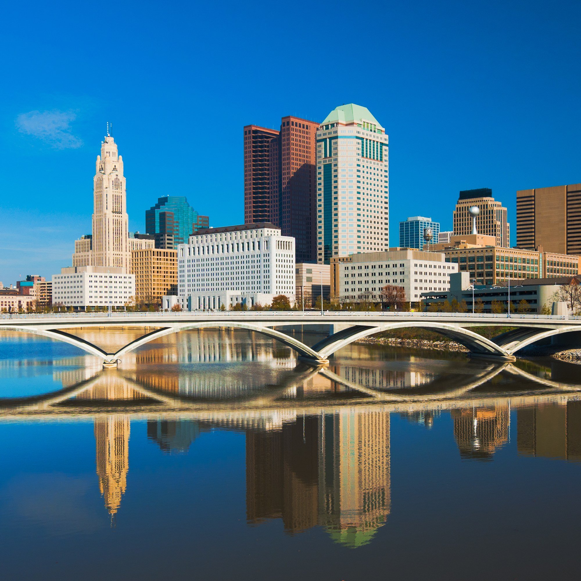 The Columbus, Ohio, skyline and a Scioto River bridge reflected in the water.