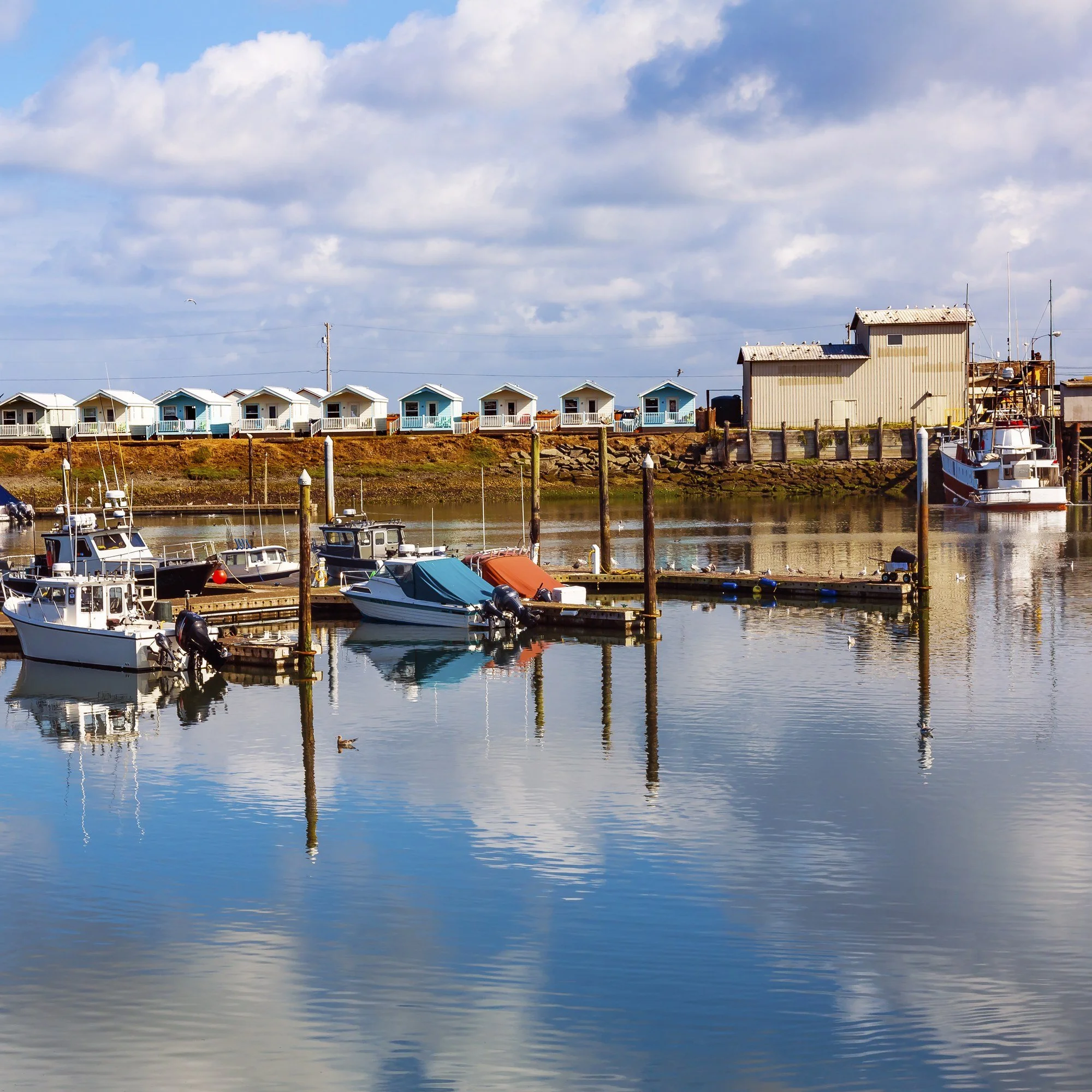 Boats docked at the marina in Westport, Washington, reflected in calm water.