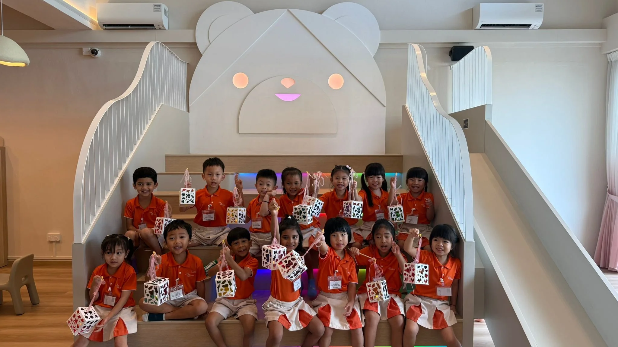 My First Skool K2 children posing for a class photo after making lanterns at Riri's Children Playloft during their lights and shadow field trip programme.