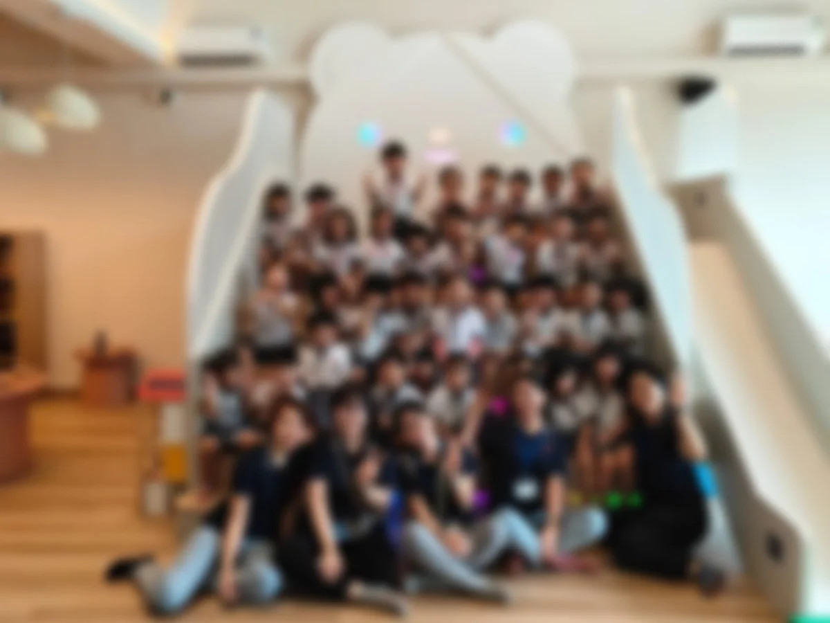 Group of children and adults in front of a whale-shaped structure indoors.