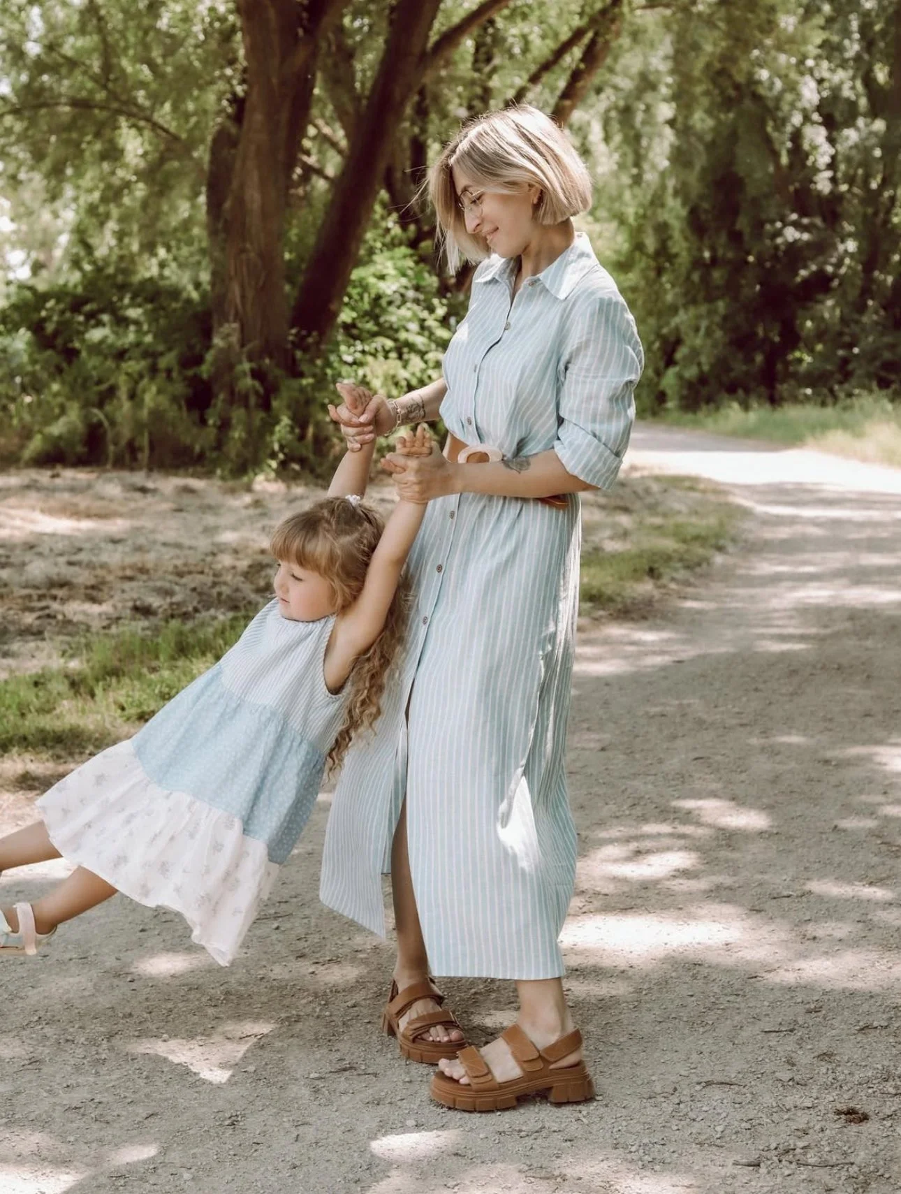 Woman in a striped dress playing with a girl in a park