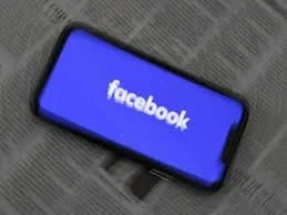 Smartphone on a surface displaying the Facebook logo on the screen.