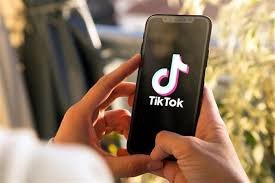 Person holding a smartphone displaying the TikTok app logo