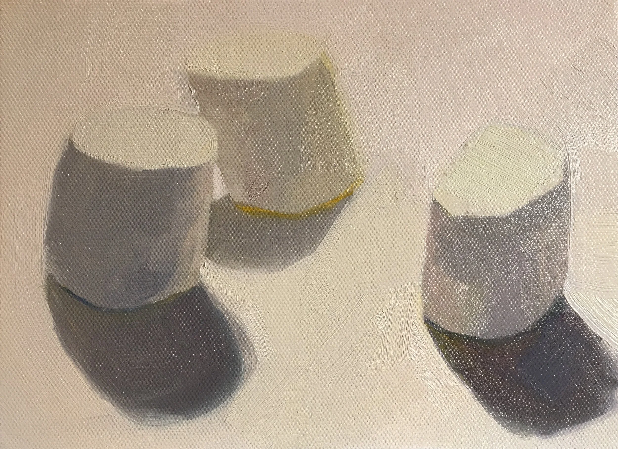 Three marshmellows on a white surface, with subtle color variations and shadows cast by the marshmellows.