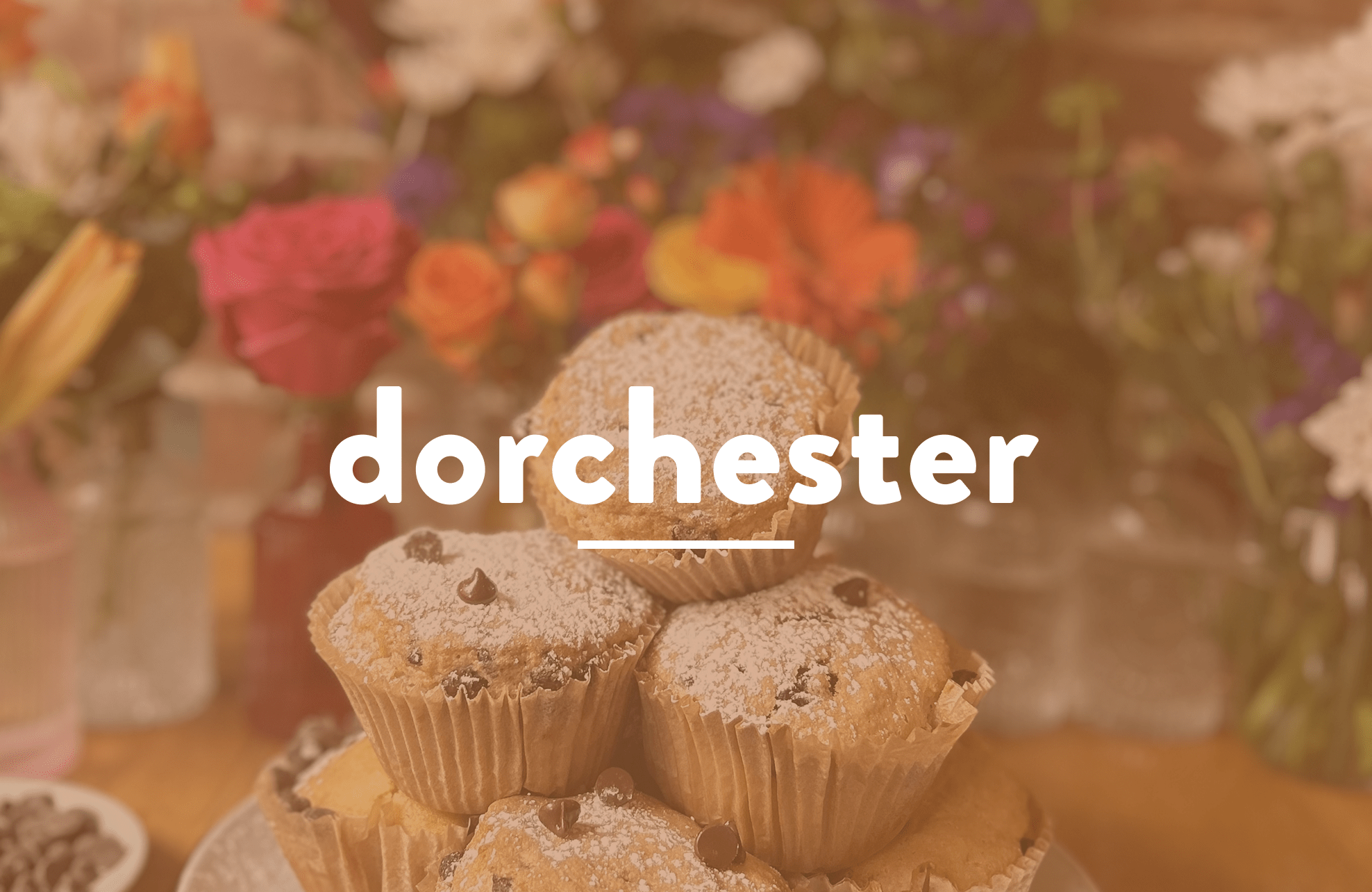 Stack of chocolate chip muffins with powdered sugar and flowers in the background