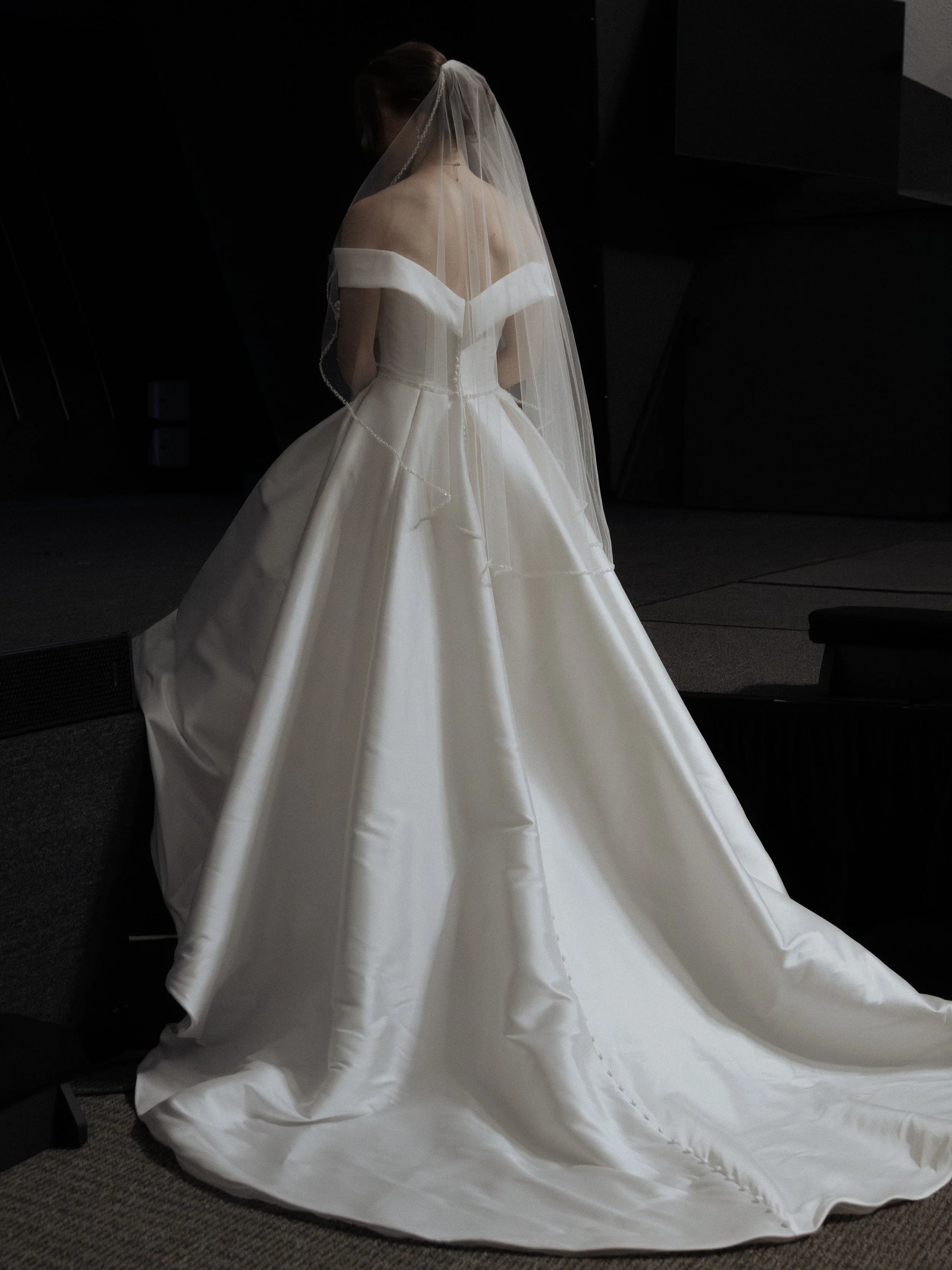 A photo of a bride walking up a set of stairs, wearing a white gown and a veil.