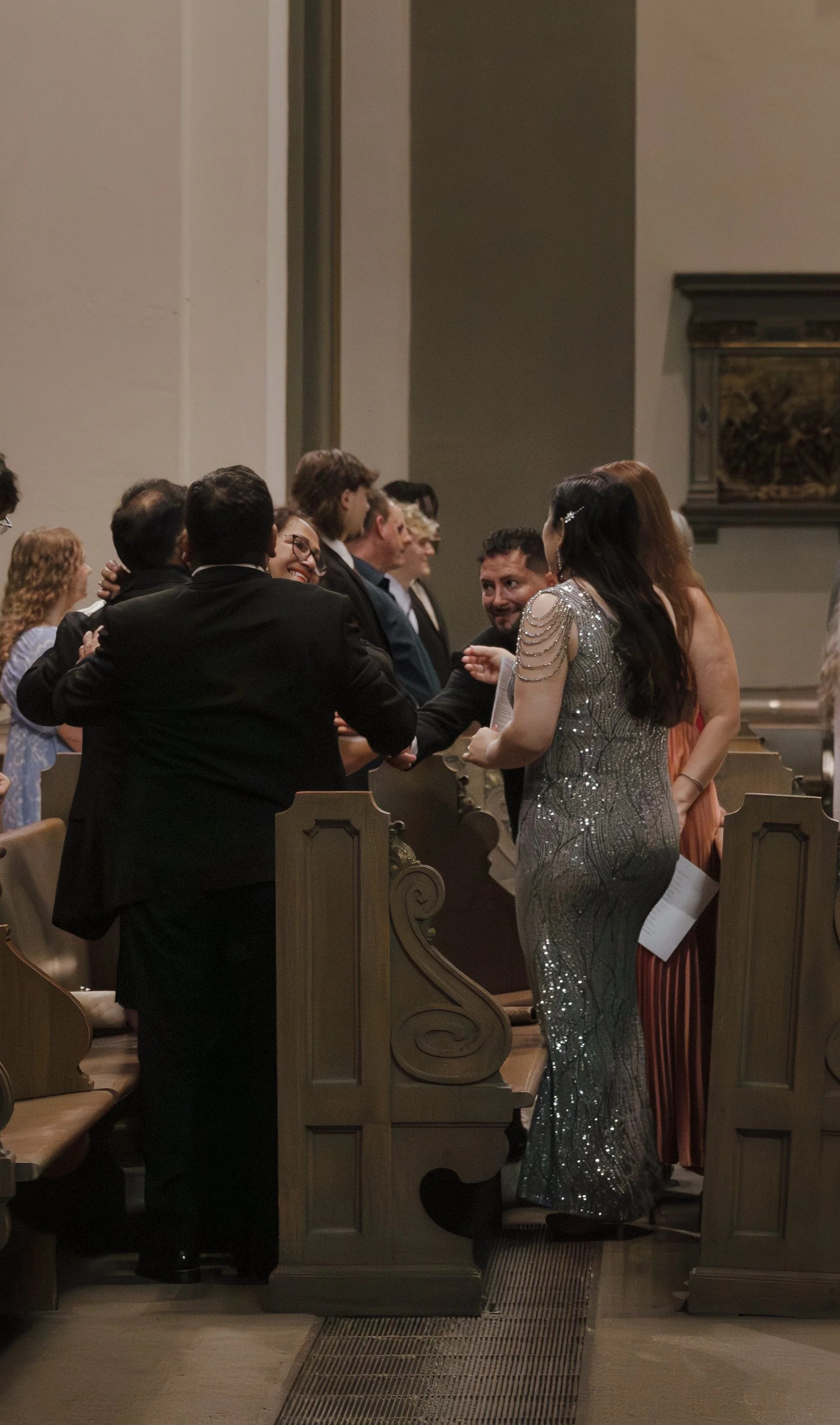 People dressed in formal attire interacting and talking inside a church or cathedral.
