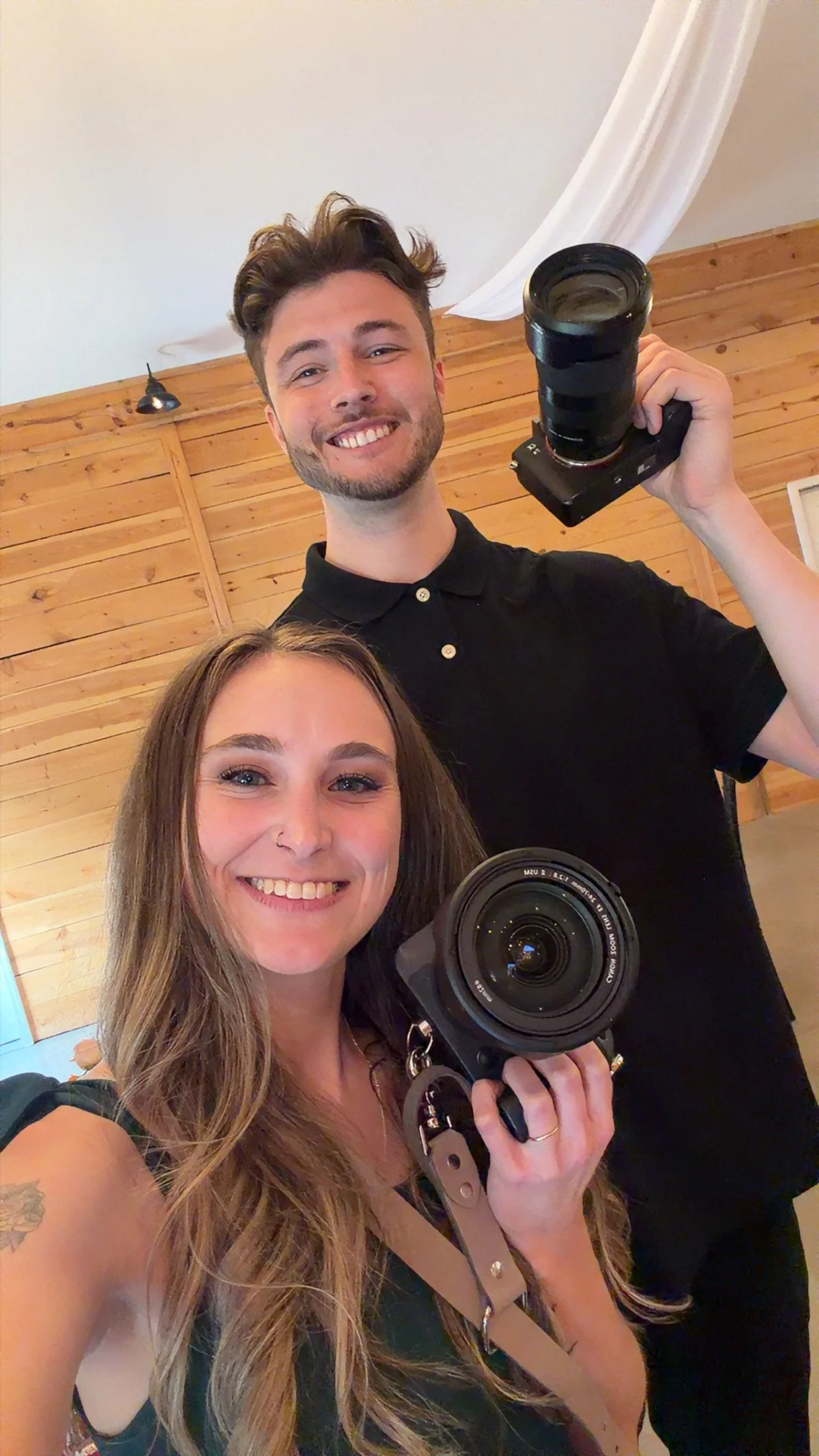 Cait and Cade with Cait Patton Photography, holding their cameras in a selfie photo together during a wedding in Bedford Virginia at the Barn at Spring Rose Lane Wedding Venue and Farm.