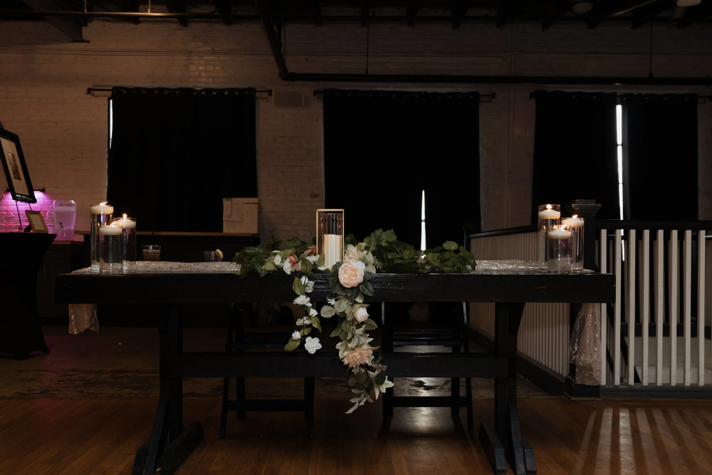 A decorated table with candles and flowers in a dimly lit room, likely prepared for a special event or celebration.