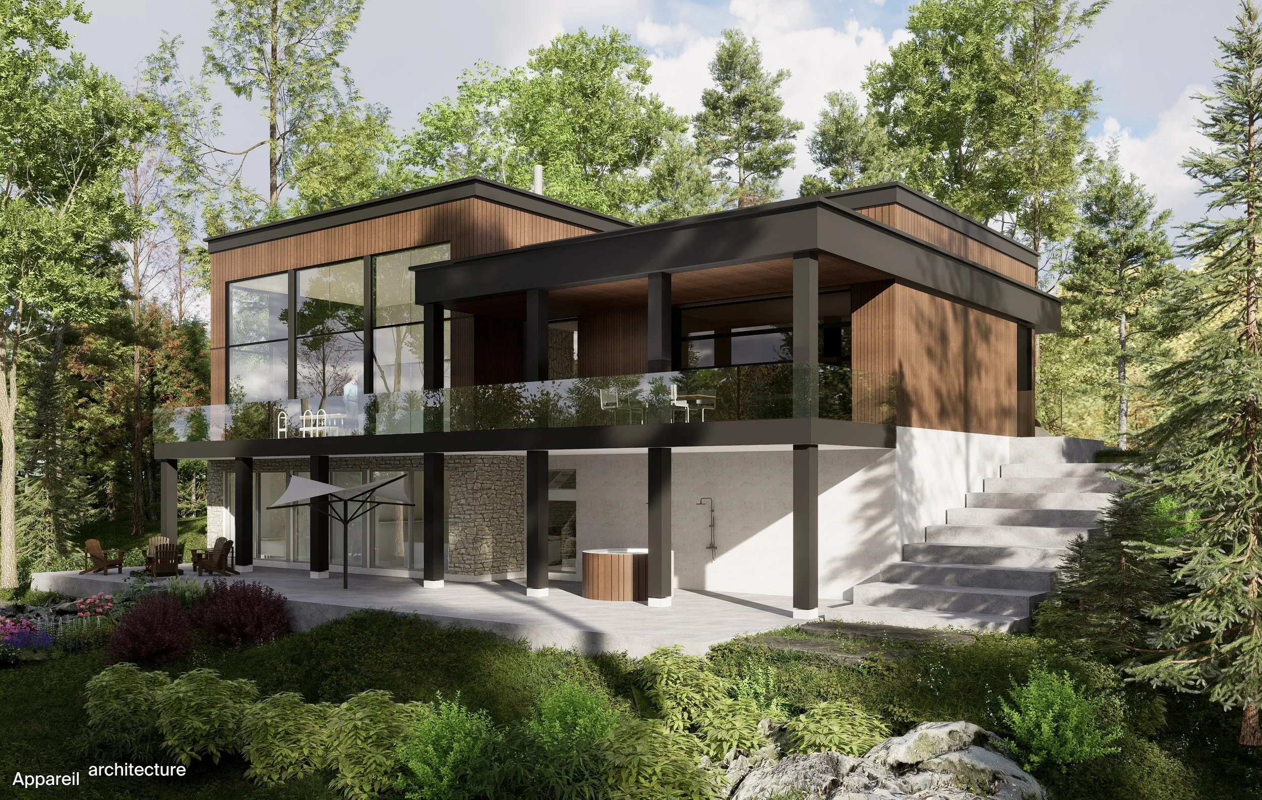 Modern two-story house in a wooded area, with large glass windows, a spacious balcony, and outdoor seating, surrounded by lush greenery and trees.