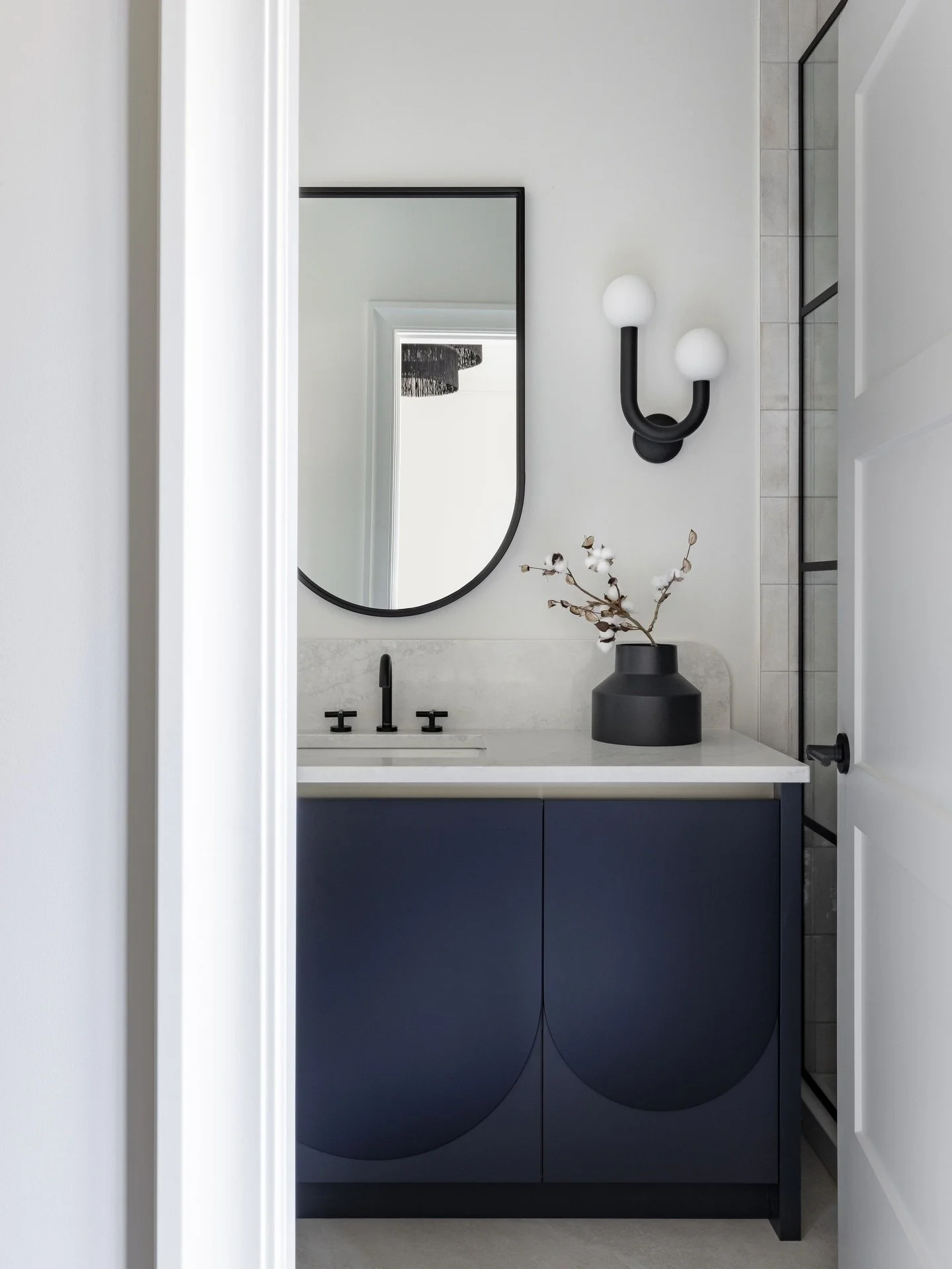 Always thinking outside the box! These scalloped cabinets make such a statement, and we played it up even more by painting them in two tones: a deep black on the upper portion and a dark charcoal below. We flipped an arched mirror upside down for a s