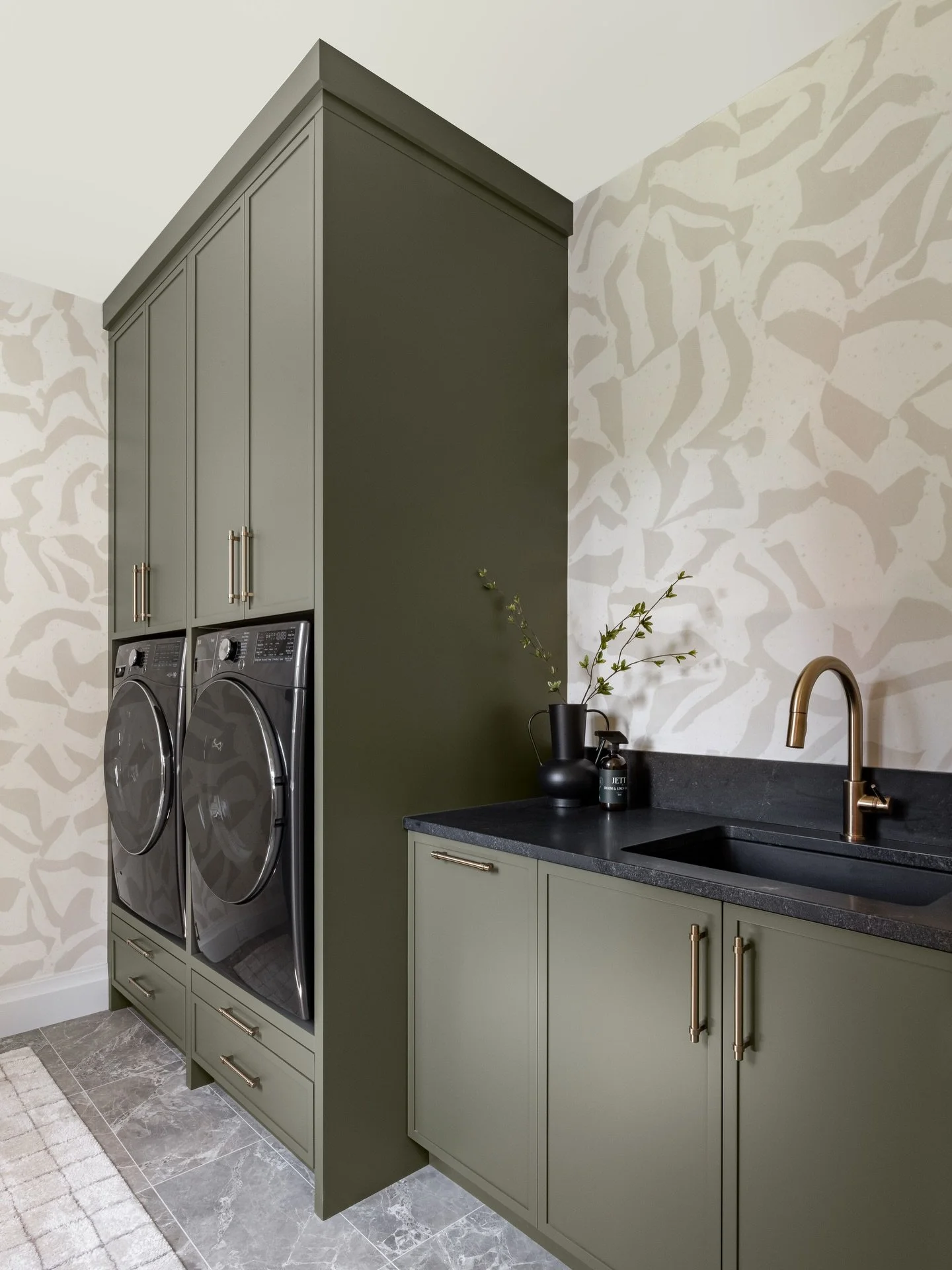 We love the quiet drama and warmth this laundry room brings, with its soft olive tones and abstract wallpaper. We chose @belartestudio&rsquo;s 𝘎𝘳𝘢𝘱𝘩𝘪𝘤 𝘊𝘭𝘢𝘺 𝘗𝘢𝘭𝘦 𝘉𝘦𝘪𝘨𝘦 for its hand-formed, ceramic-inspired pattern, adding texture a