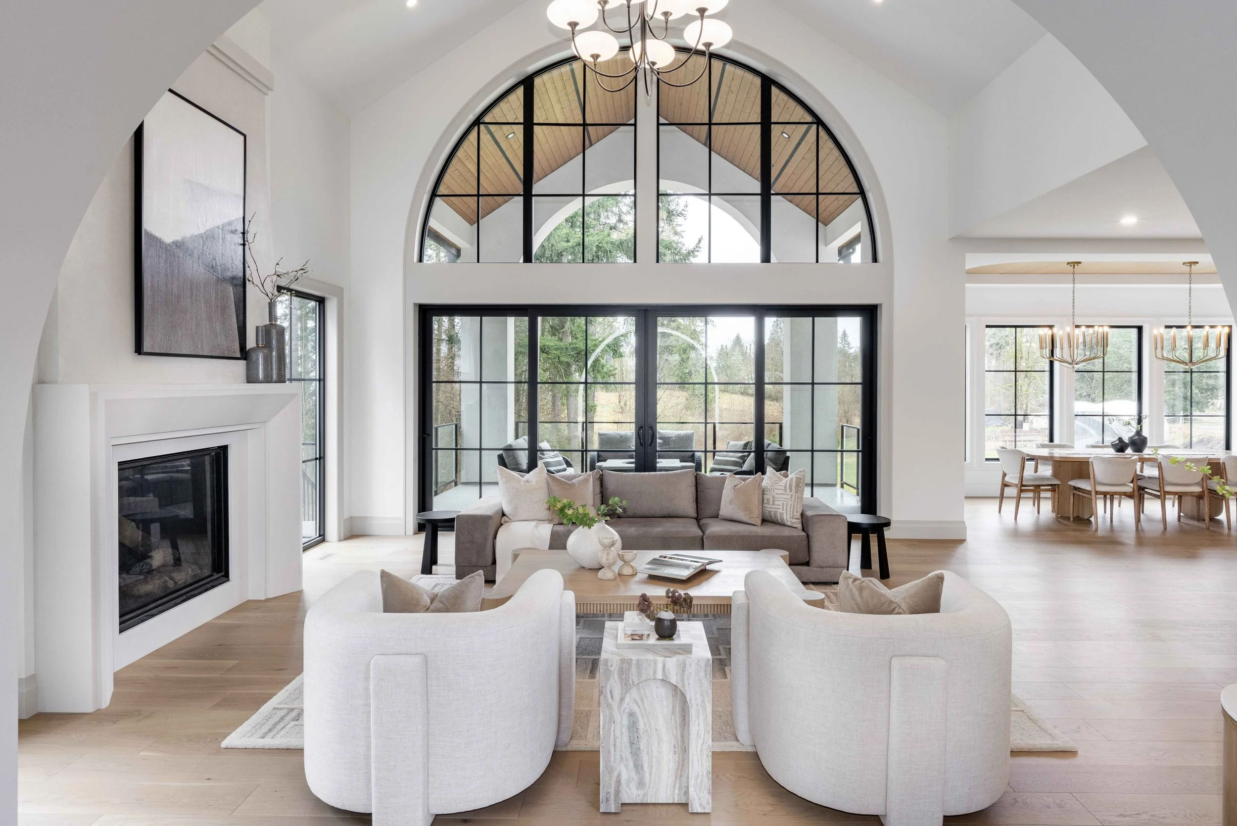 Bright living room with large arched window, modern furniture, and a fireplace.