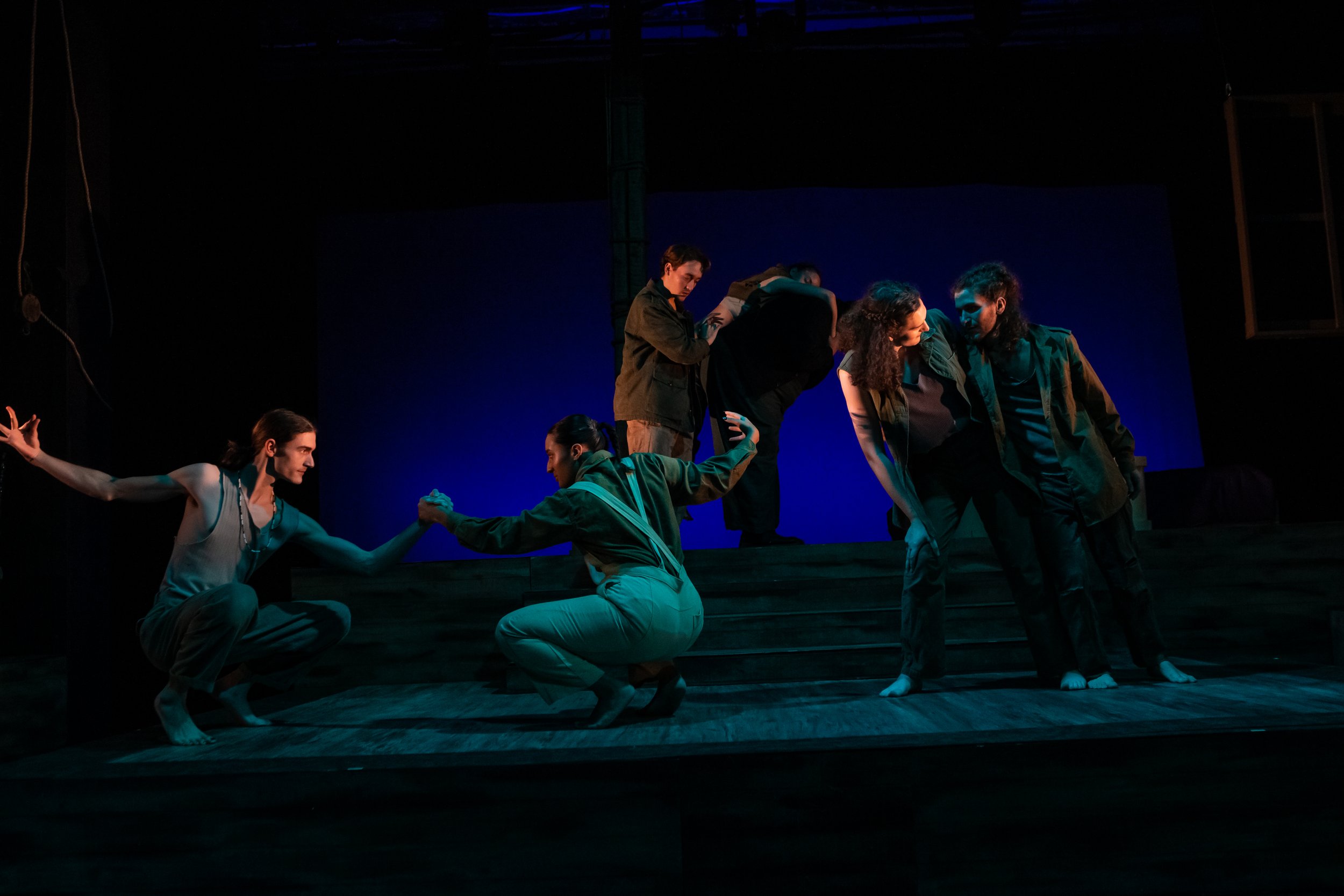 Theatrical performance with actors on stage with blue lighting