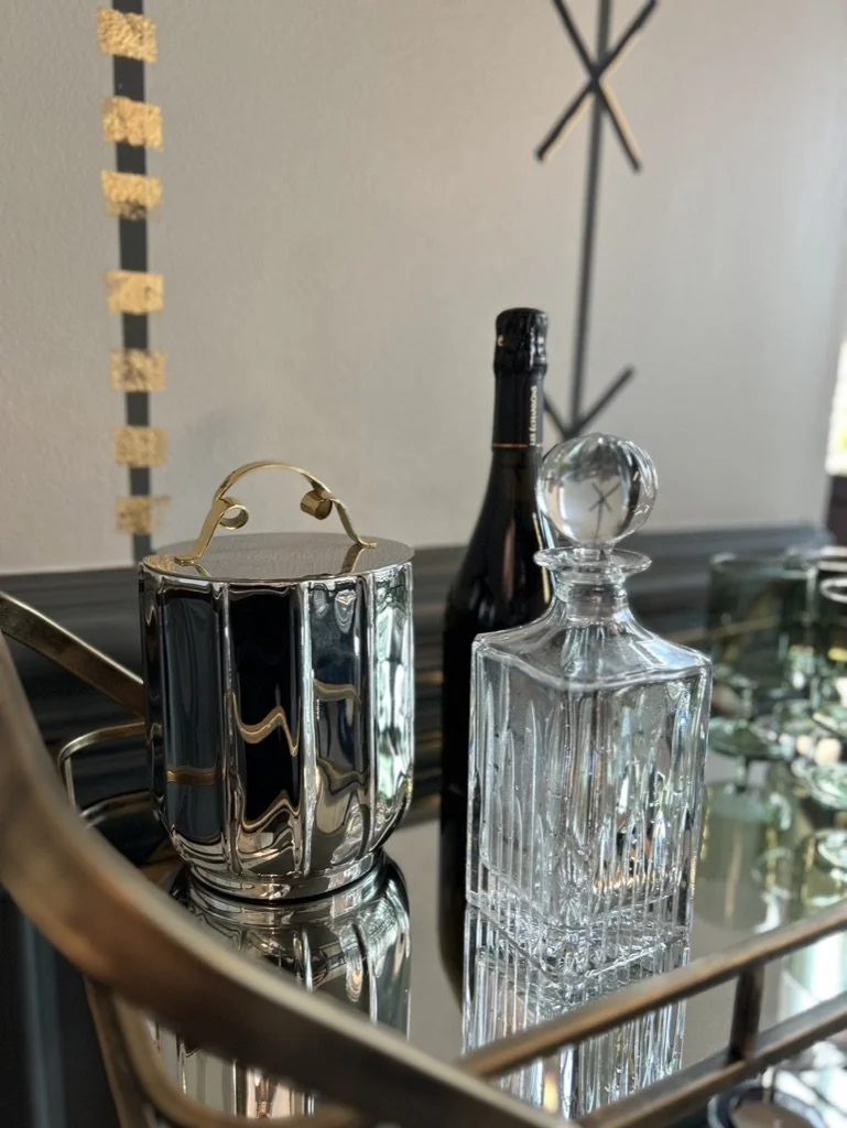 Decorative glass bottles and a metallic container placed on a reflective surface.