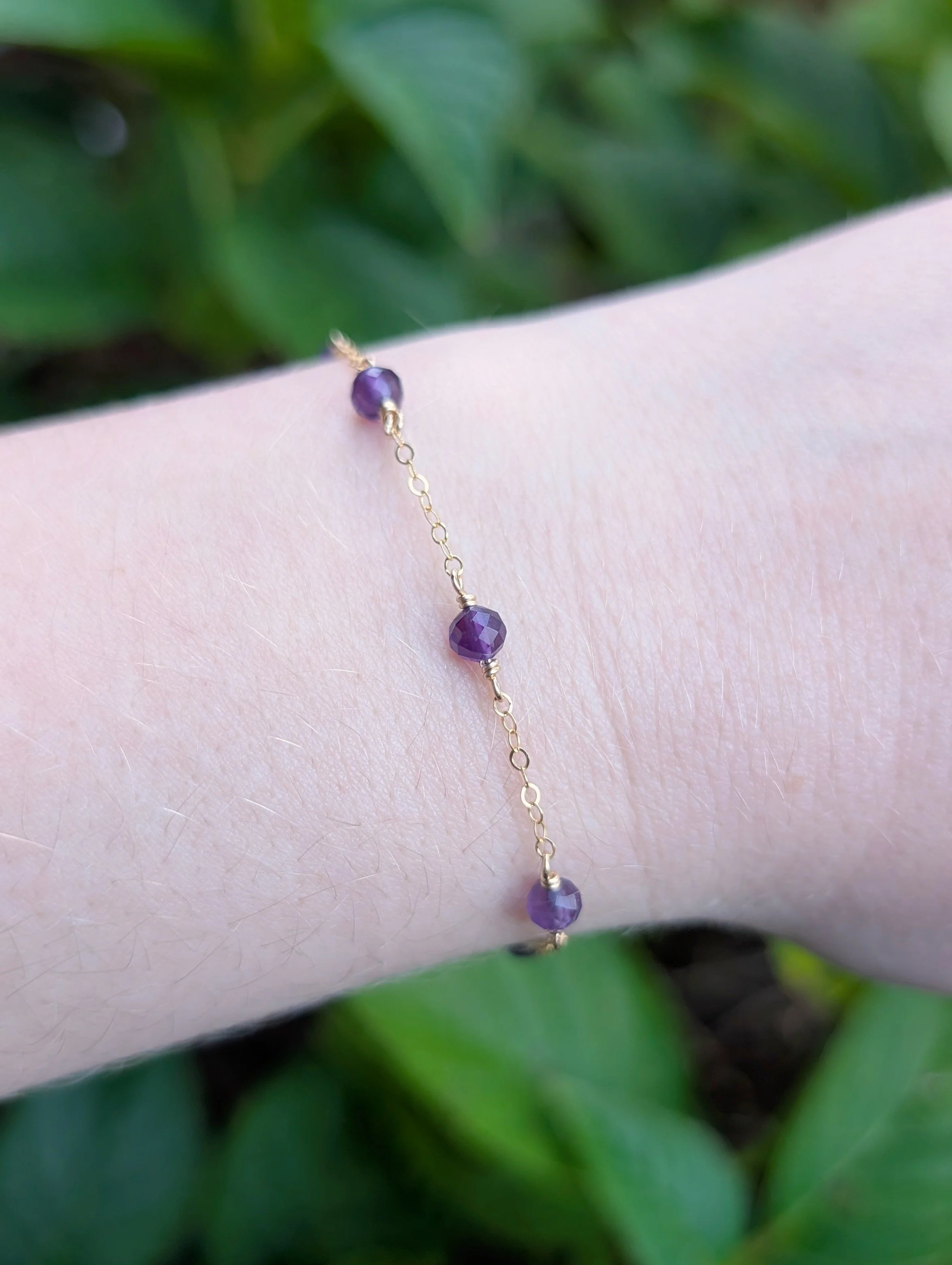 Bracelet made with faceted purple amethyst beads and gold filled chain modeled on wrist.