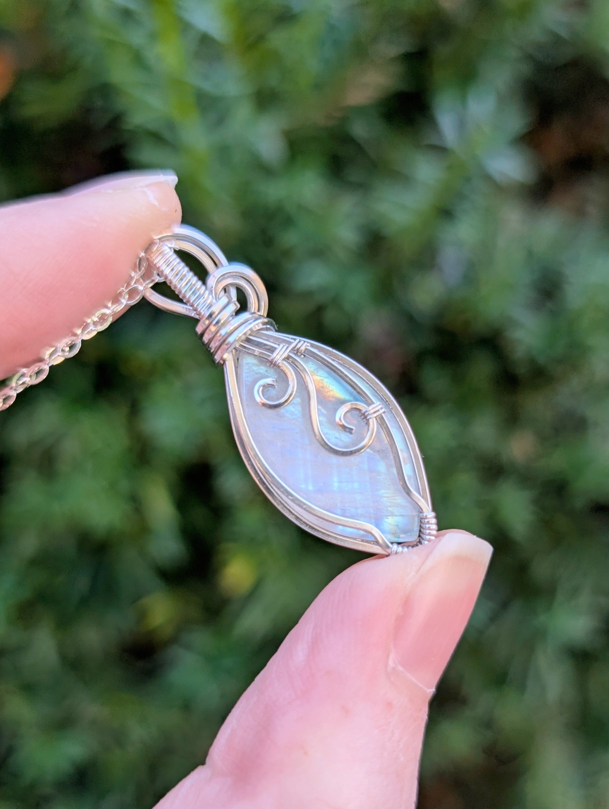 The back of a marquis-shaped rainbow moonstone pendant wrapped in sterling silver.