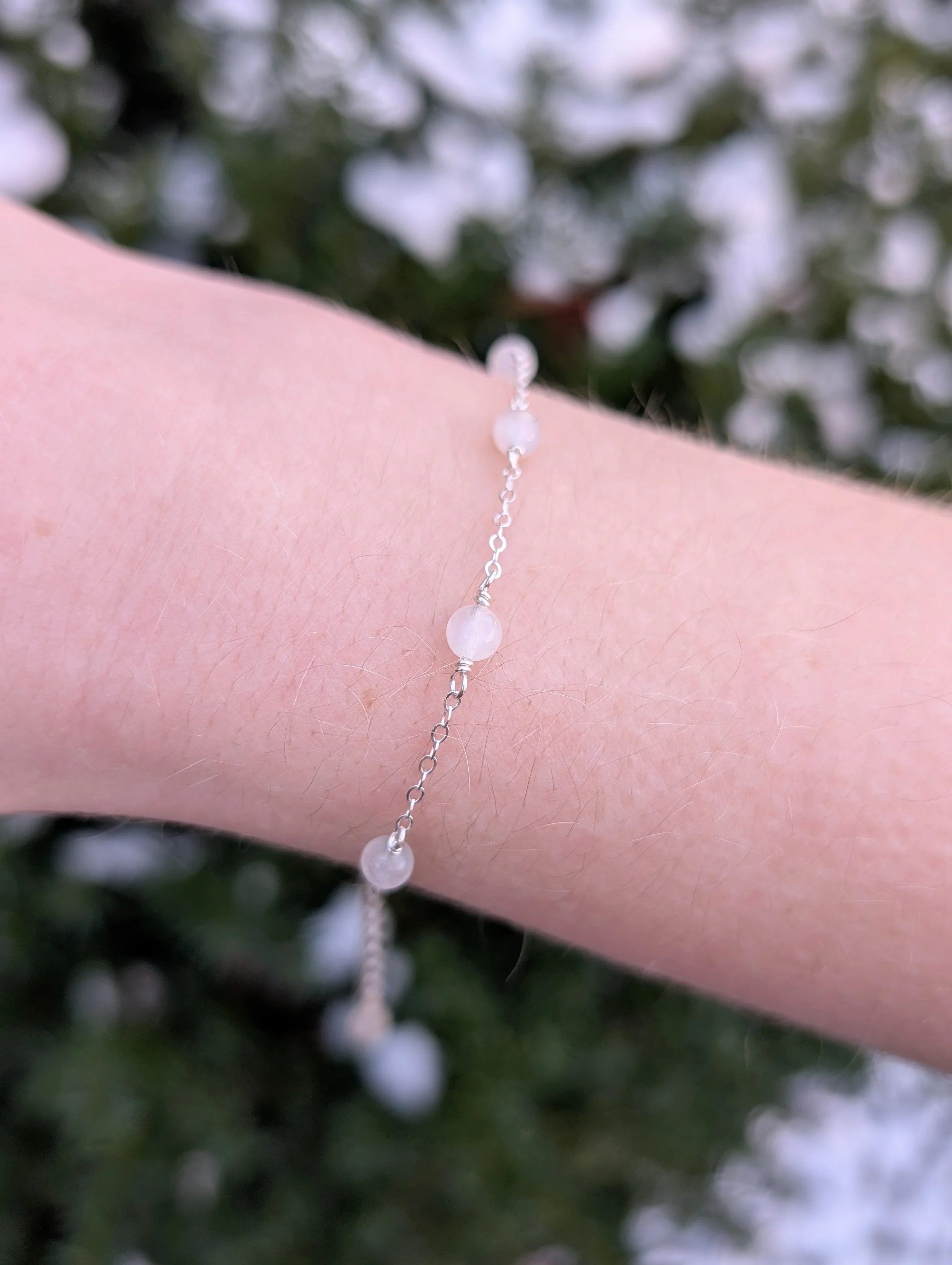 Bracelet made with white moonstone beads and sterling silver chain modeled on wrist.