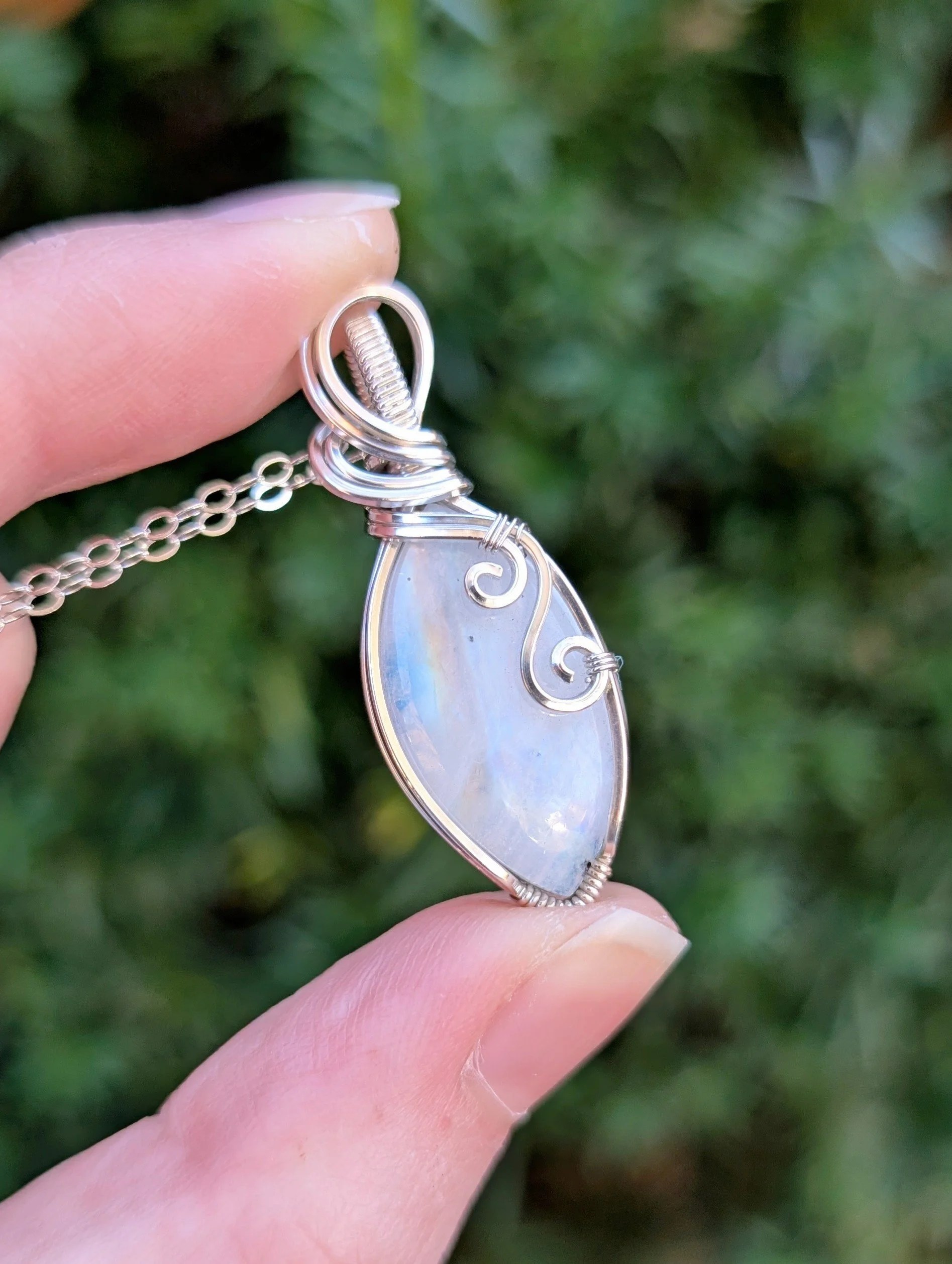Pendant made with a rainbow moonstone marquis wrapped in sterling silver with swirl designs