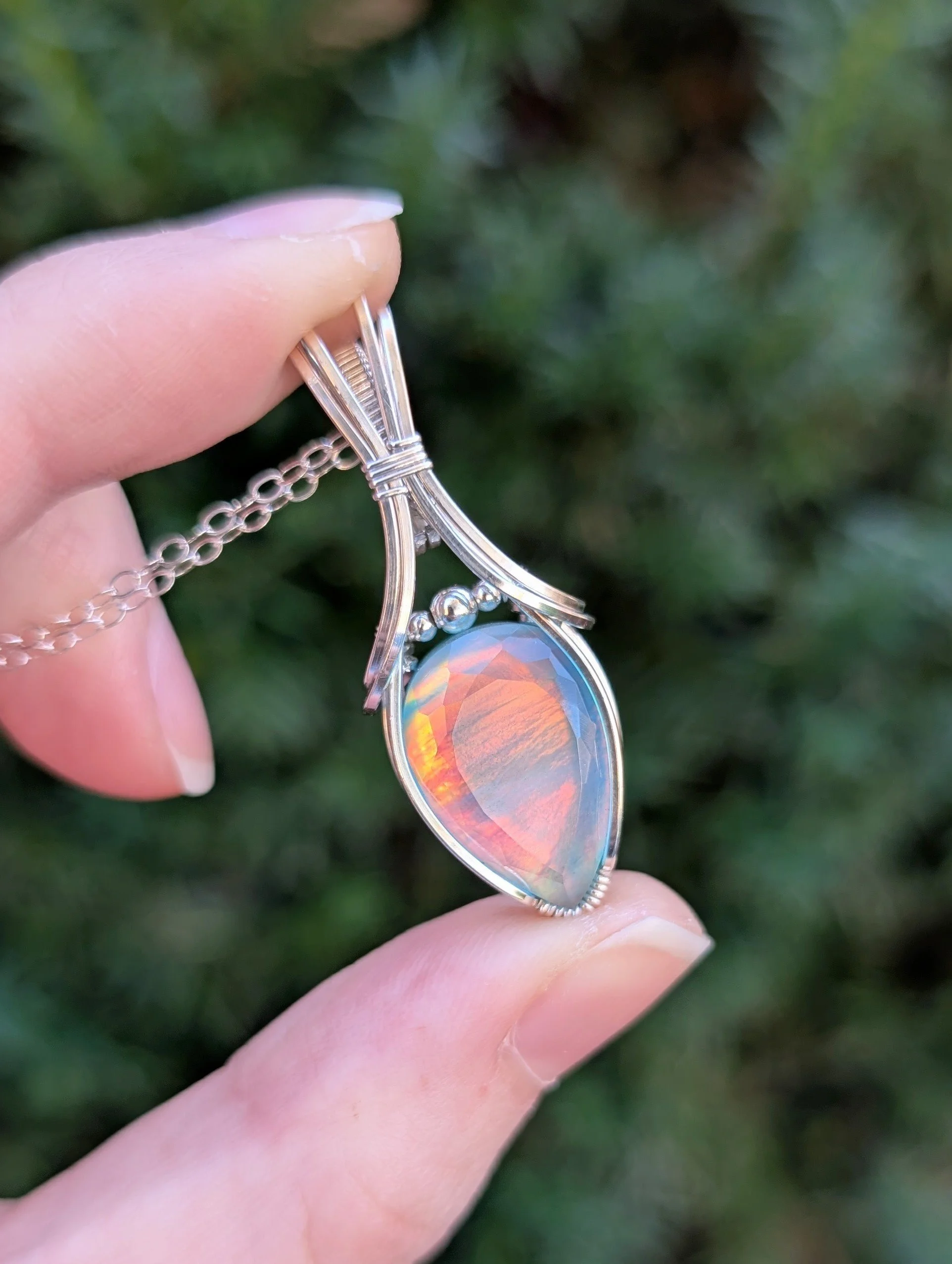 Pendant made with a colorful teardrop-shaped opal stone wrapped in sterling silver