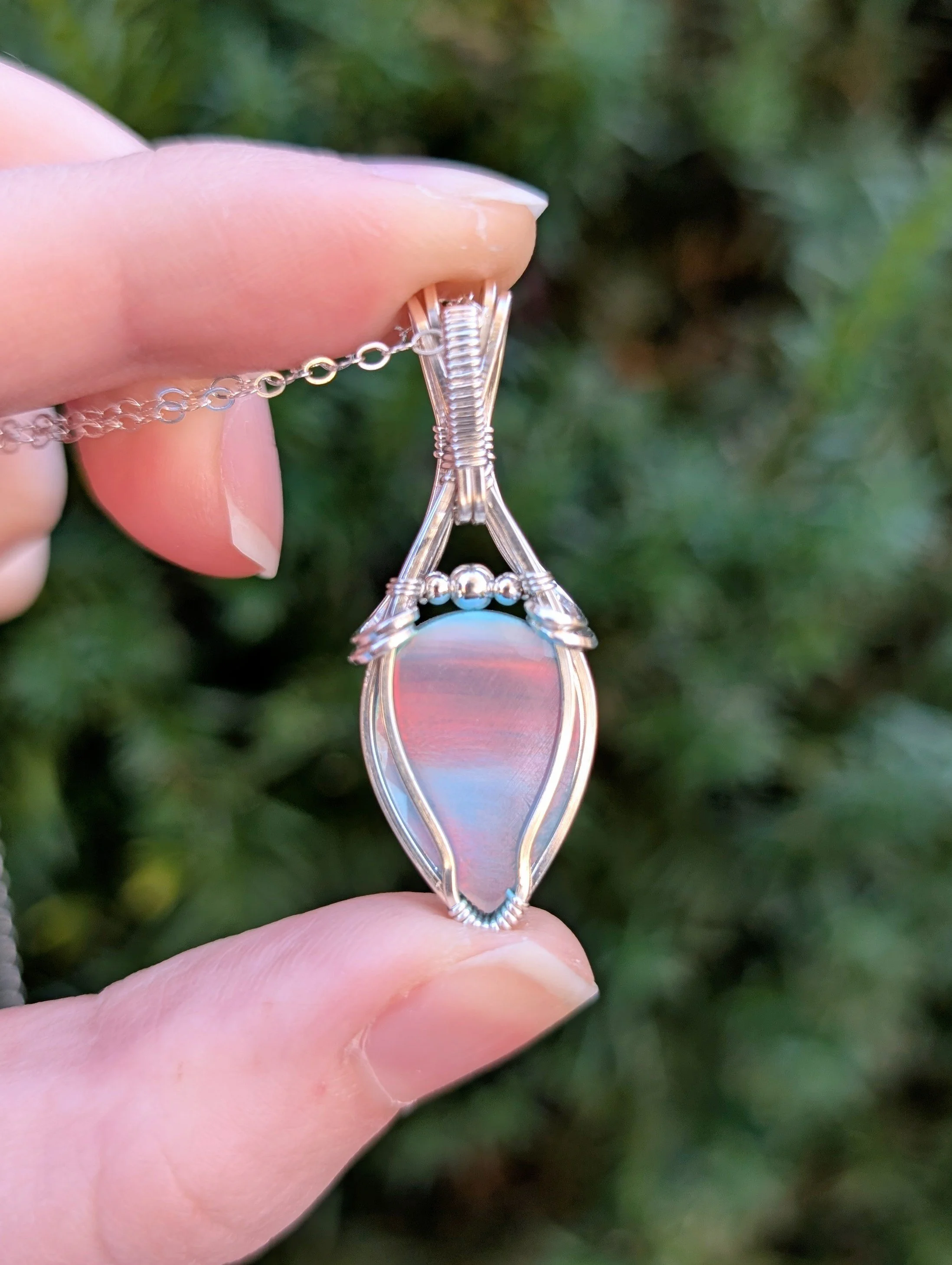 The back of the Vaeloria necklace, featuring a teardrop aurora opal stone wrapped in sterling silver wire.