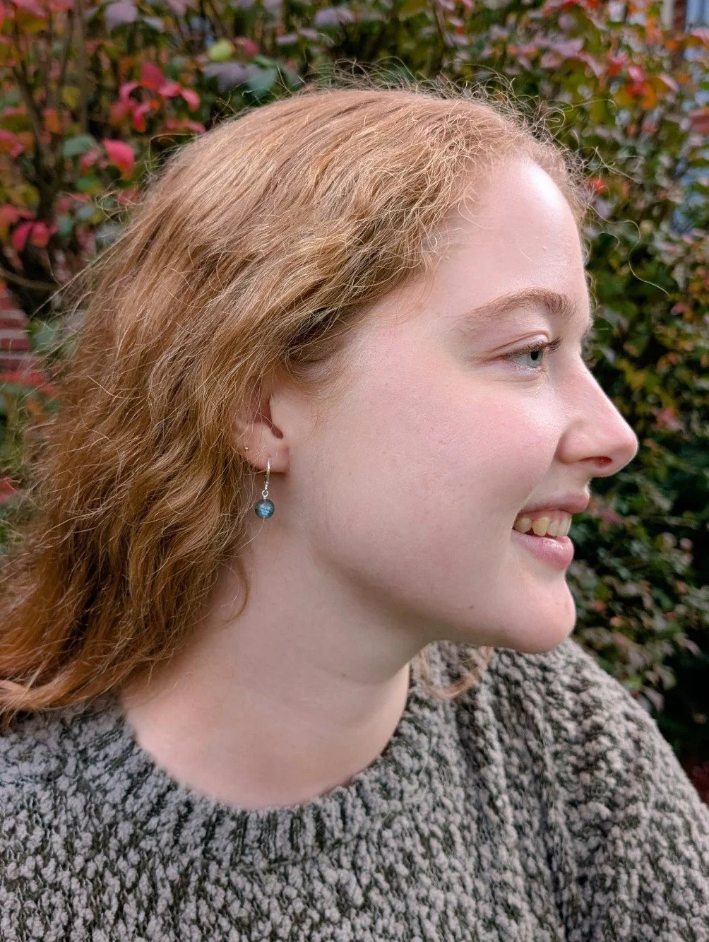 Sterling silver round leverback earrings with labradorite bead dangles featured on model's ear.