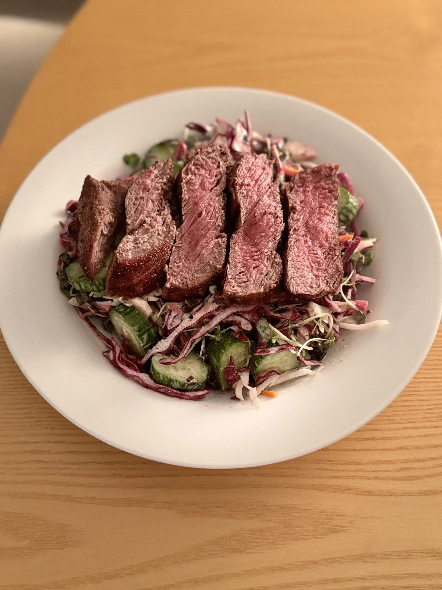 Sliced steak over a fresh green salad