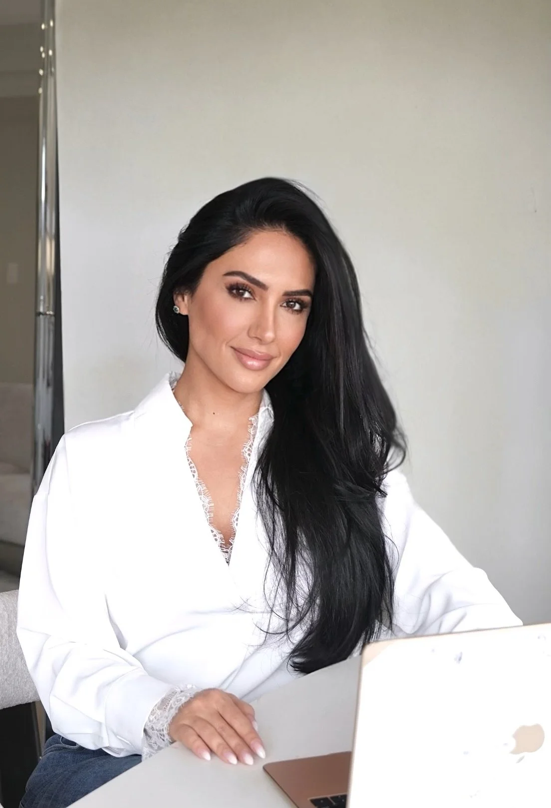 Sydney Sajadi, founder of Sanadi Life, seated at her desk in a white blouse