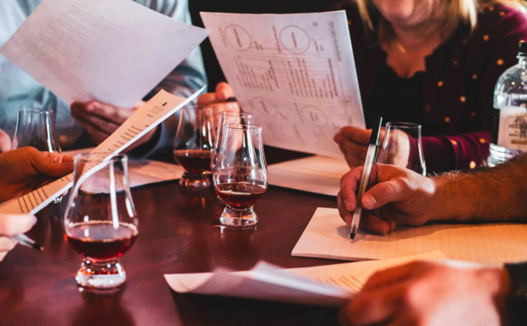 Group holding papers at table with glasses of dark liquid