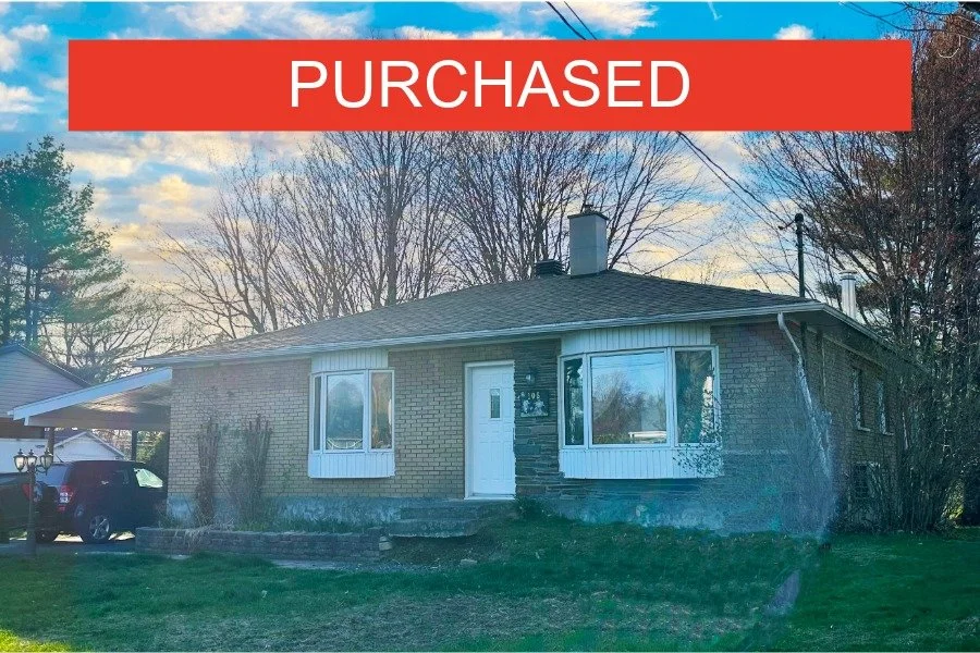 Front view of a brick house with a sign on the image that says 'Purchased'.