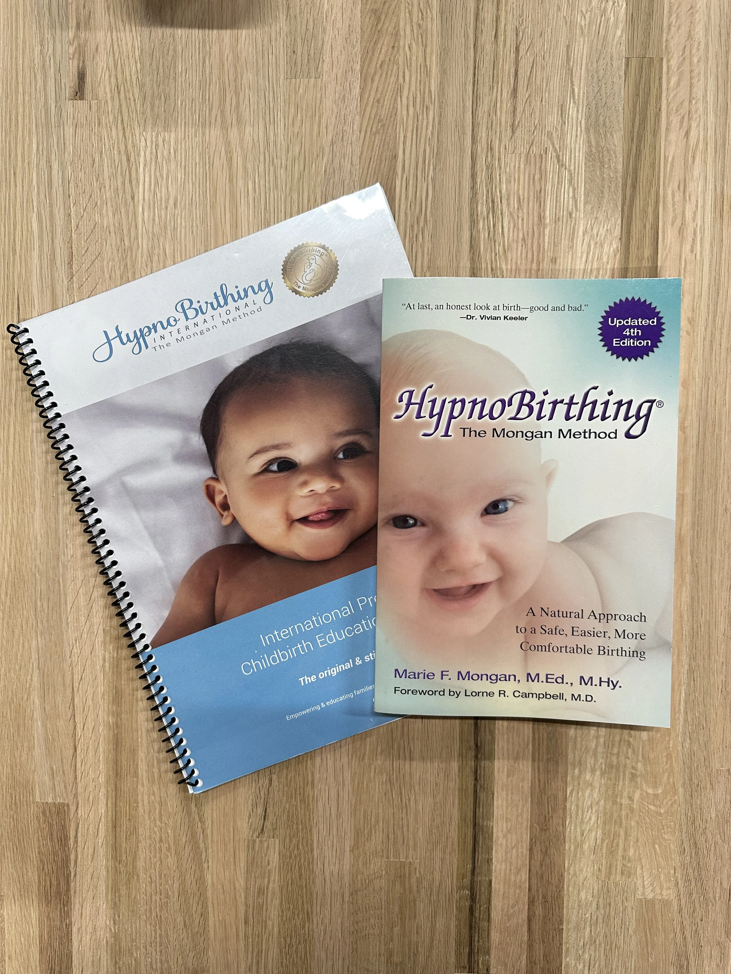 Two books on natural childbirth, featuring photos of smiling babies with light skin on a wooden surface.