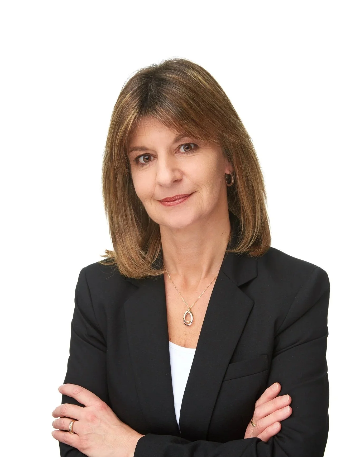 Professional business headshot of Sarah in a black blazer with her arms crossed against a white background.