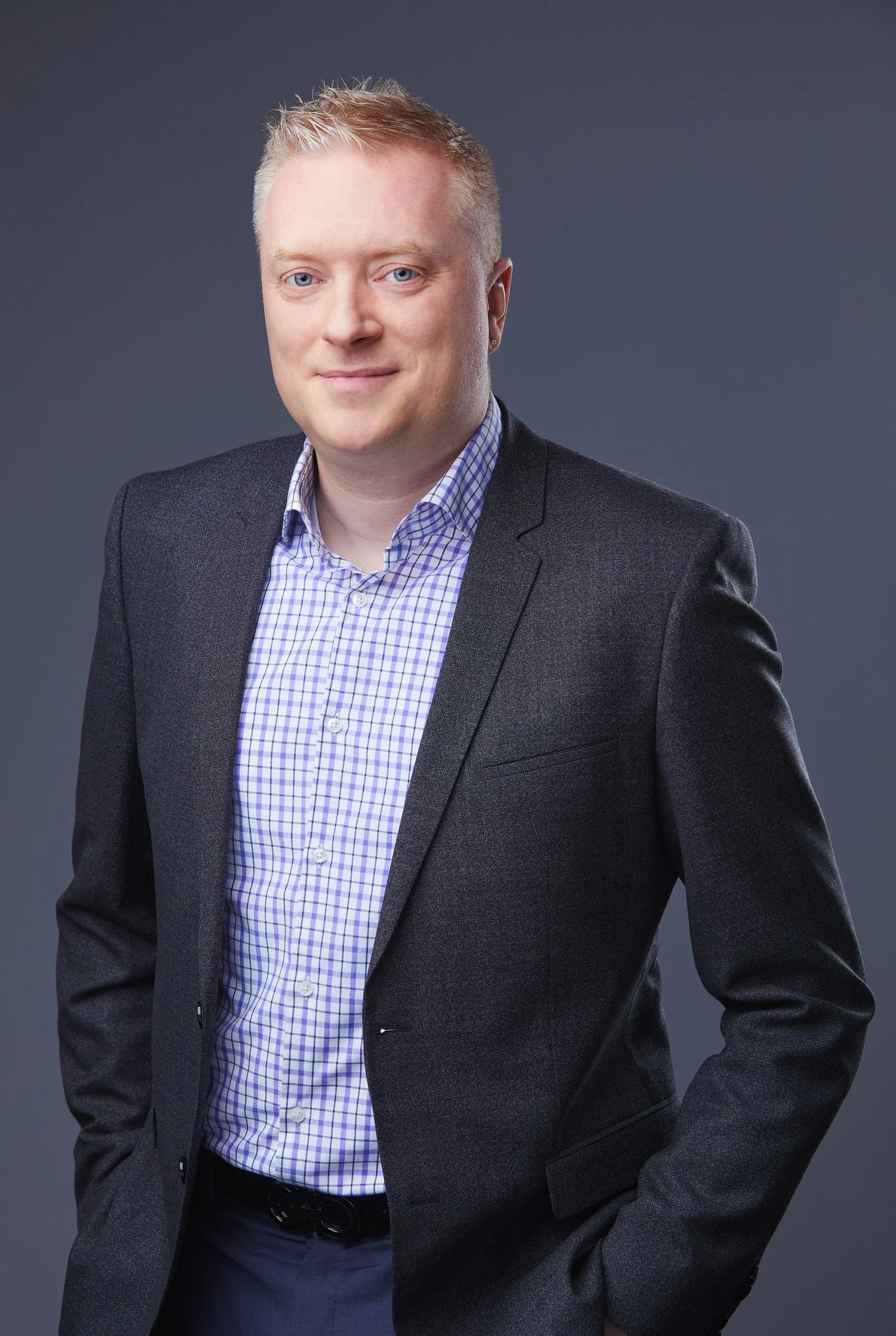 Professional business headshot of Cameron in a dark blazer against a charcoal studio background.